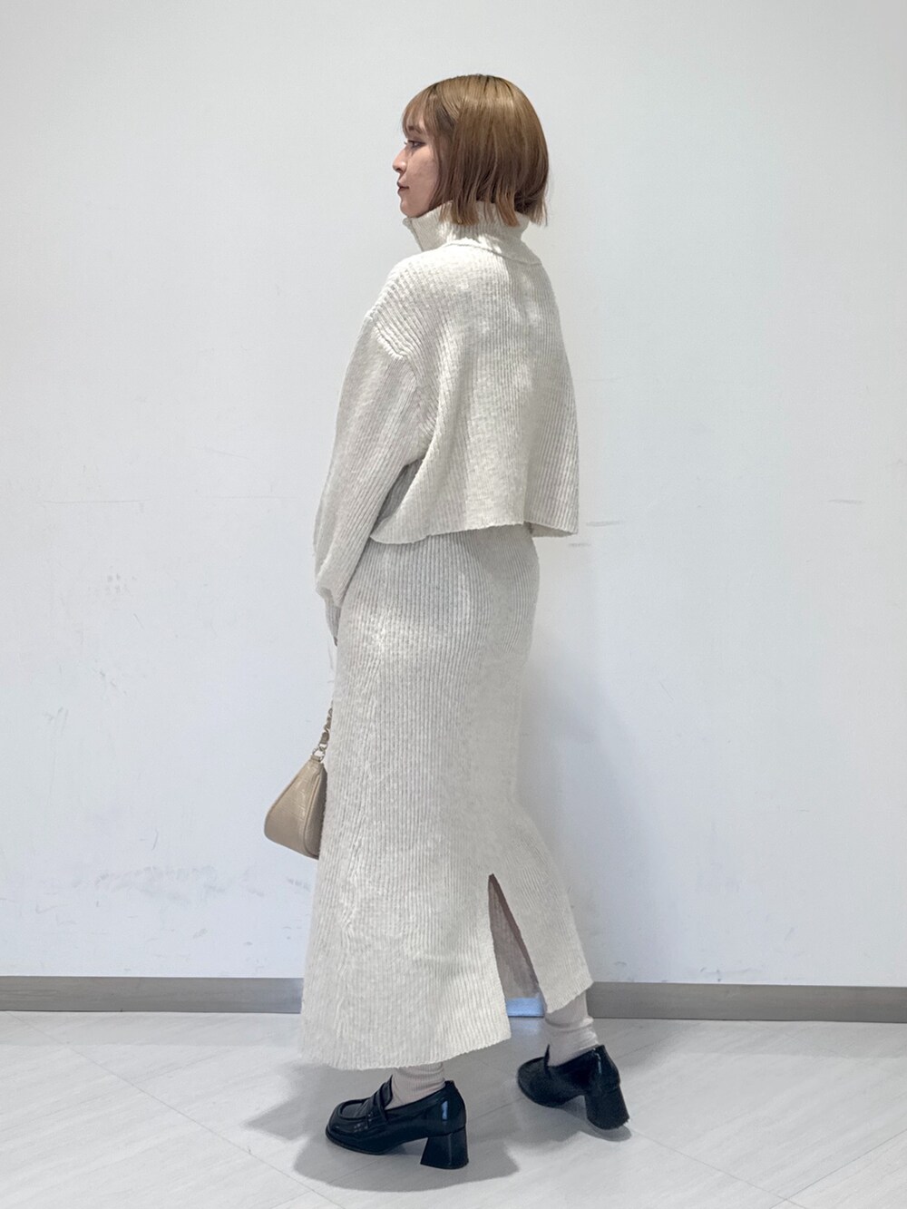 ホワイト系のワンピース、ベージュ系のトートバッグ、ブラック系のローファーを着用したレディースの冬コーディネートの3枚目の写真