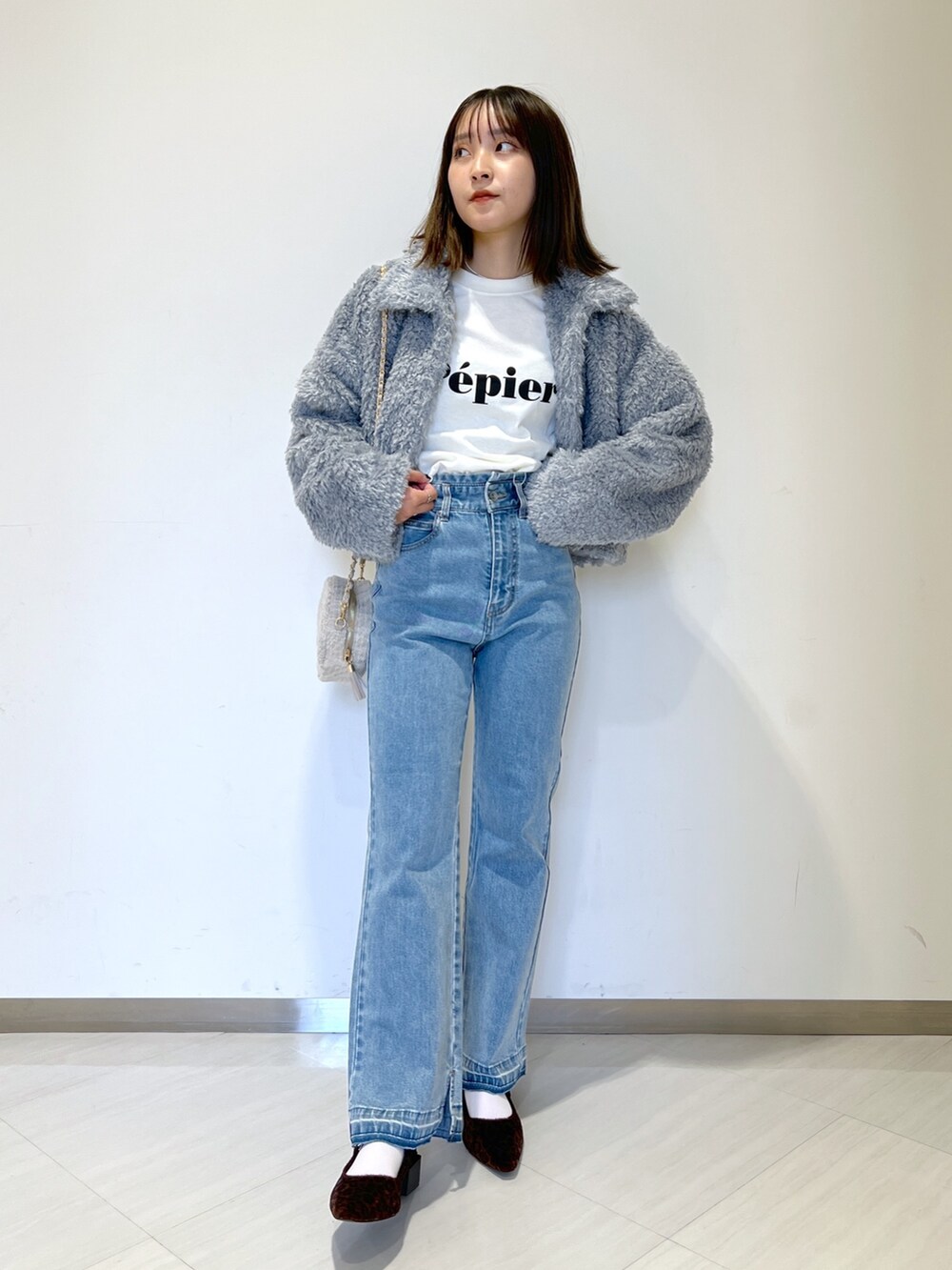 ブルー系のブルゾン、ブルー系のデニムパンツ、ベージュ系のショルダーバッグを着用したレディースの秋コーディネートの4枚目の写真