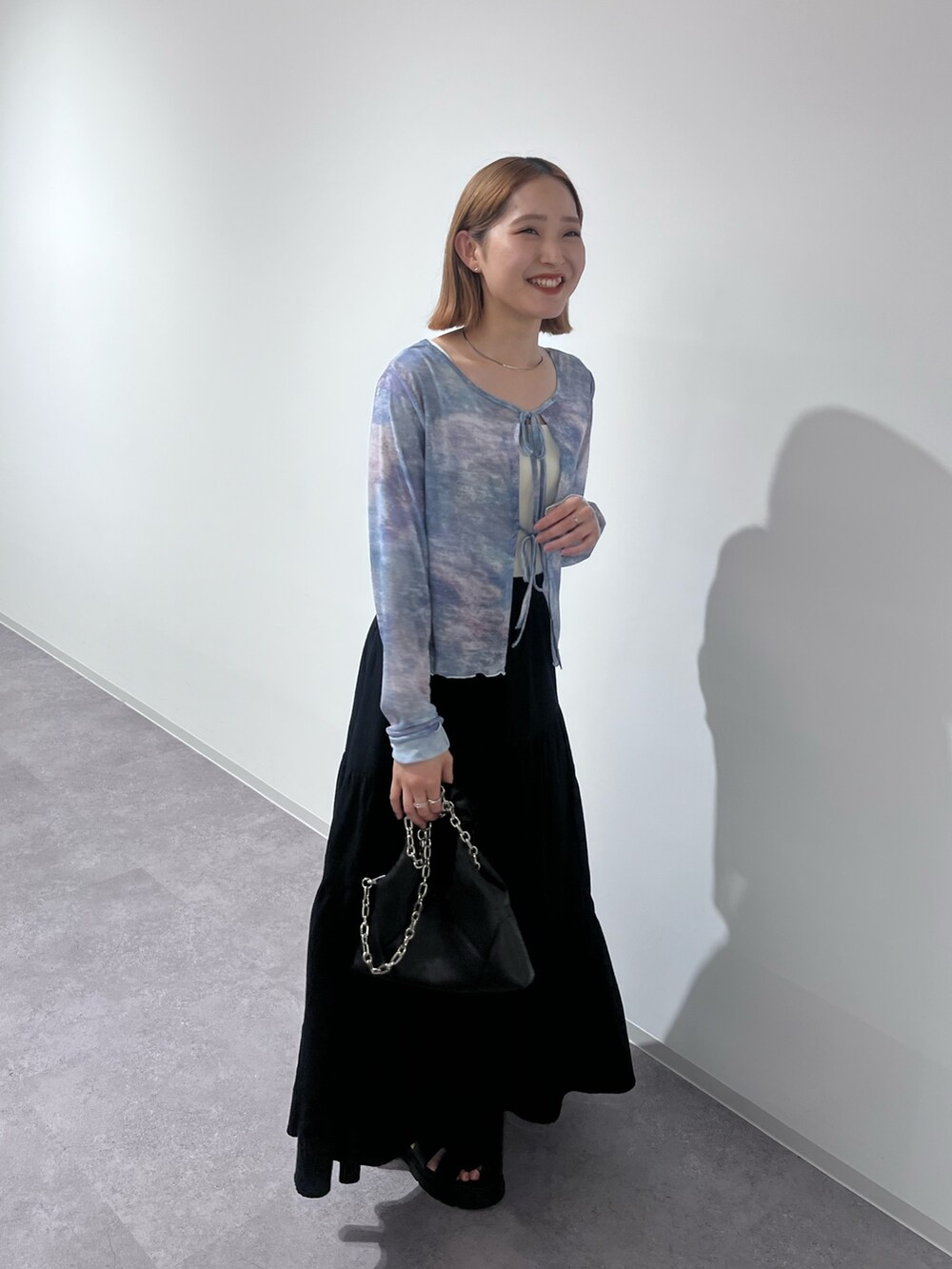 ブラック系のトートバッグ、ブラック系のスカート、ブラック系のサンダルを着用したレディースの夏コーディネートの3枚目の写真