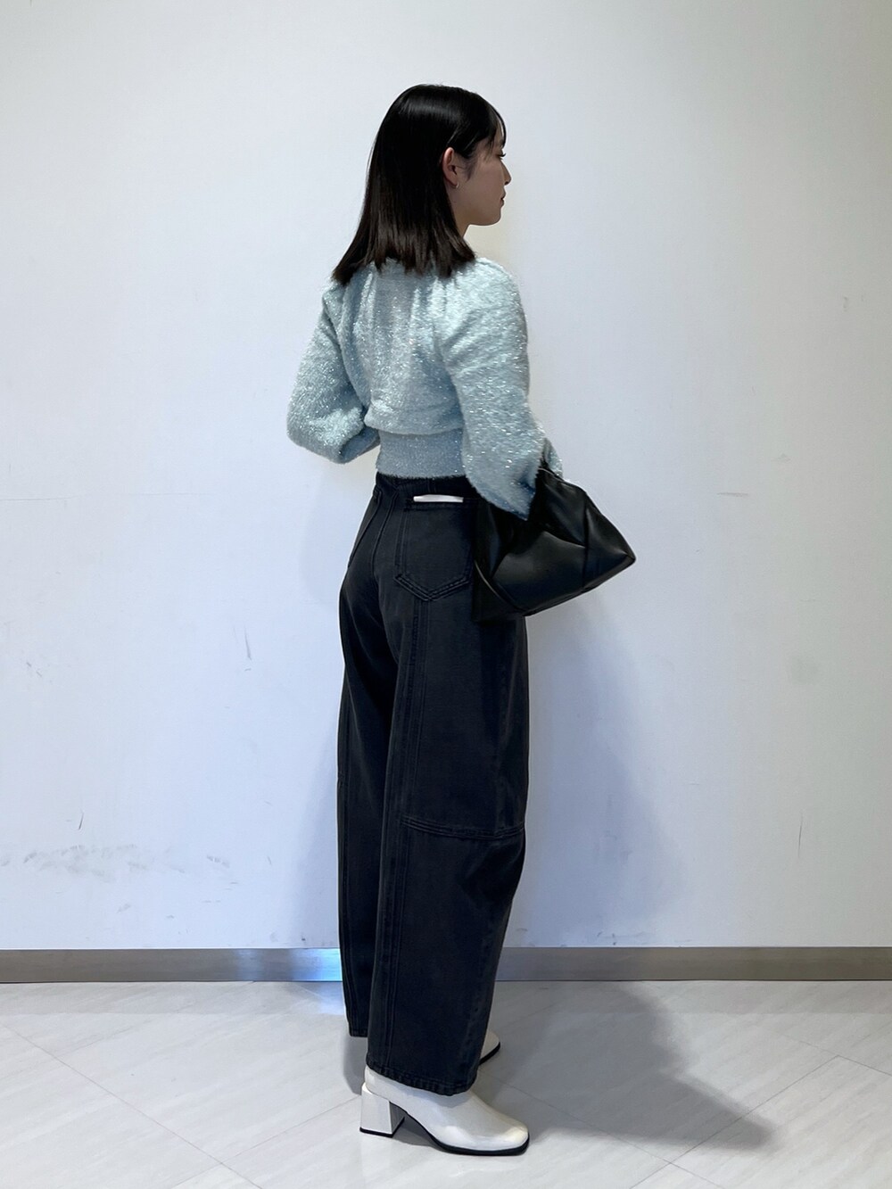 グリーン系のニット/セーター、ブラック系のデニムパンツ、ブラック系のショルダーバッグを着用したレディースの冬コーディネートの5枚目の写真