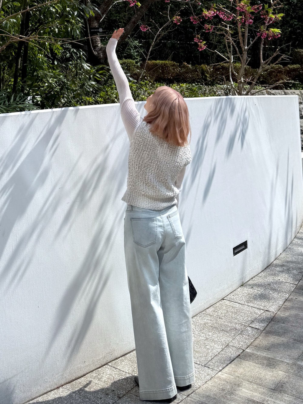 ホワイト系のベスト、ホワイト系のニット/セーター、ブルー系のデニムパンツを着用したレディースの春コーディネートの5枚目の写真