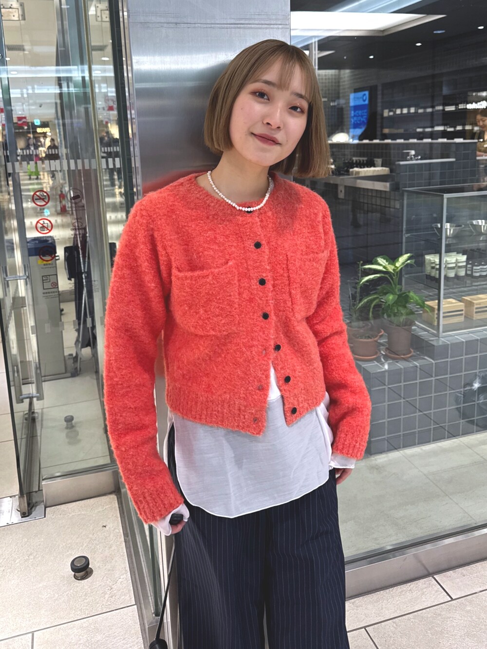 ホワイト系のTシャツ/カットソー、ピンク系のカーディガン/ボレロ、ブルー系のスラックスを着用したレディースの冬コーディネートの2枚目の写真