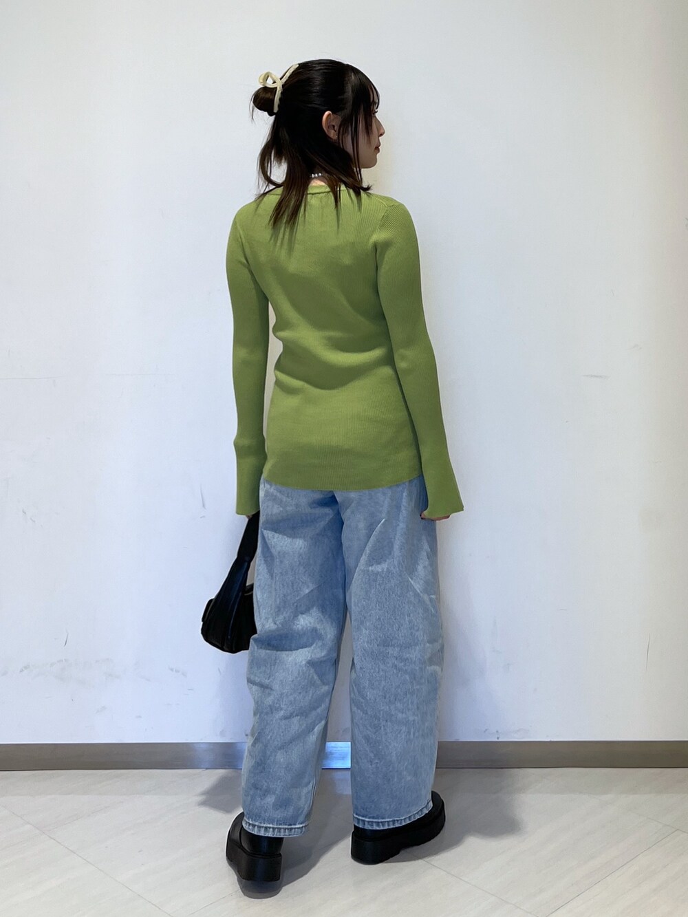 グリーン系のカーディガン/ボレロ、ブラック系のショルダーバッグ、ブルー系のデニムパンツを着用したレディースの冬コーディネートの5枚目の写真