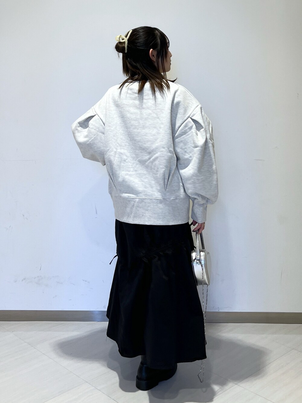 ホワイト系のスウェット、シルバー系のショルダーバッグ、ブラック系のスカートを着用したレディースの冬コーディネートの5枚目の写真