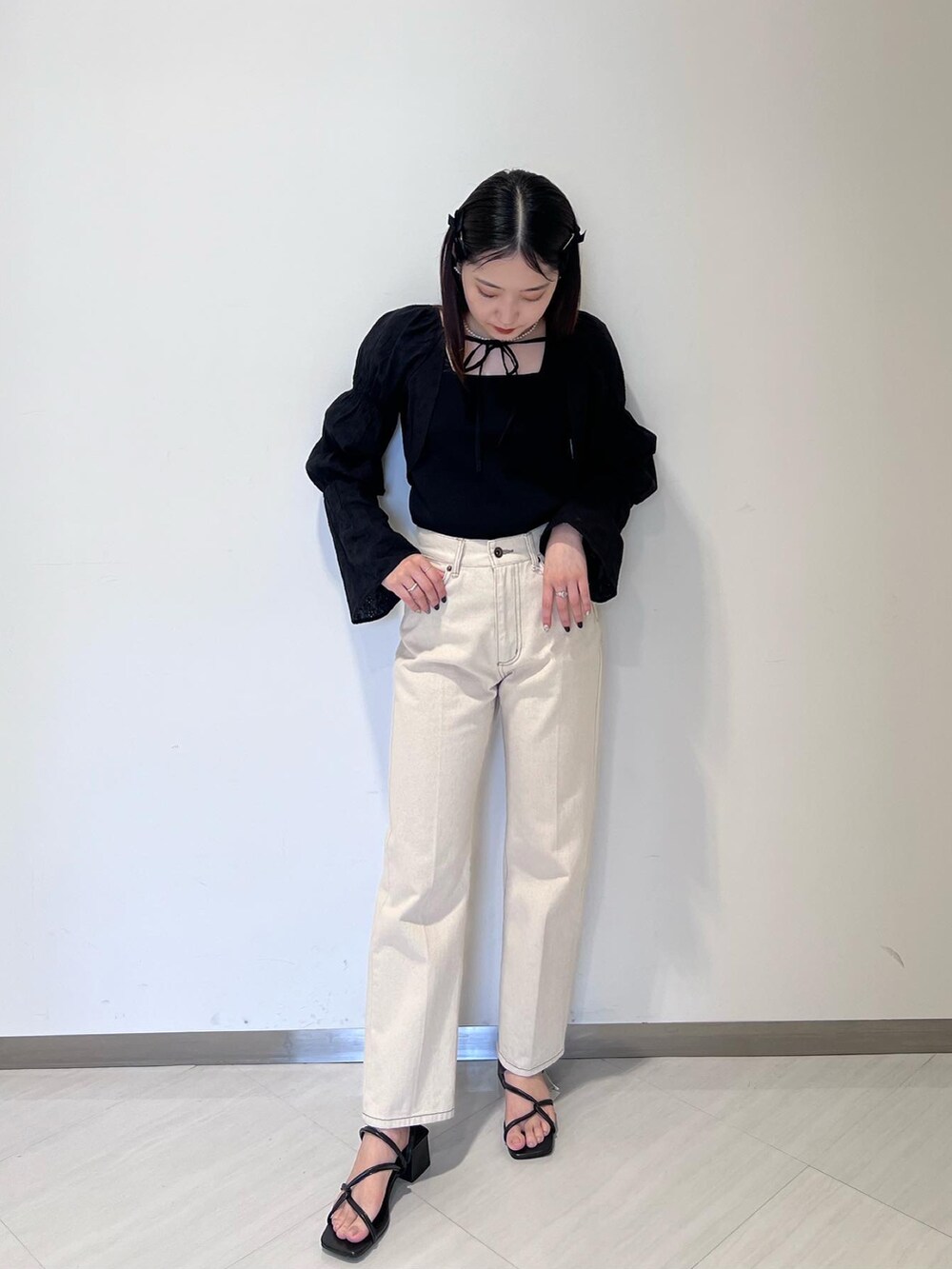 ブラック系のニット/セーター、ブラック系のカーディガン/ボレロ、ホワイト系のデニムパンツを着用したレディースの春コーディネートの2枚目の写真