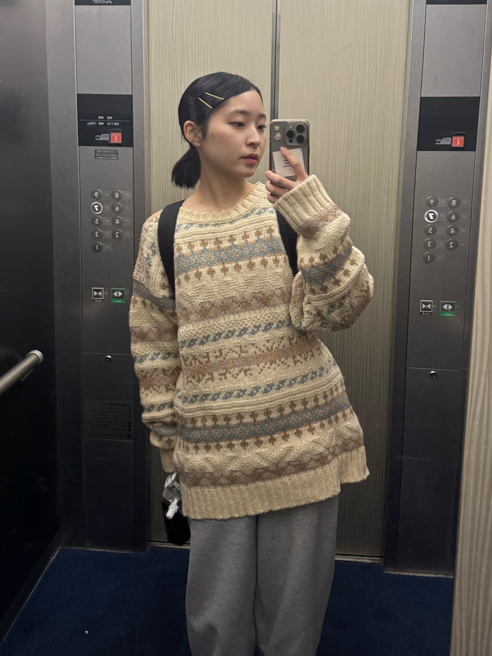 ベージュ系のトップス、ブラック系のバッグ、グレー系のパンツを着用したレディースの秋コーディネートの3枚目の写真