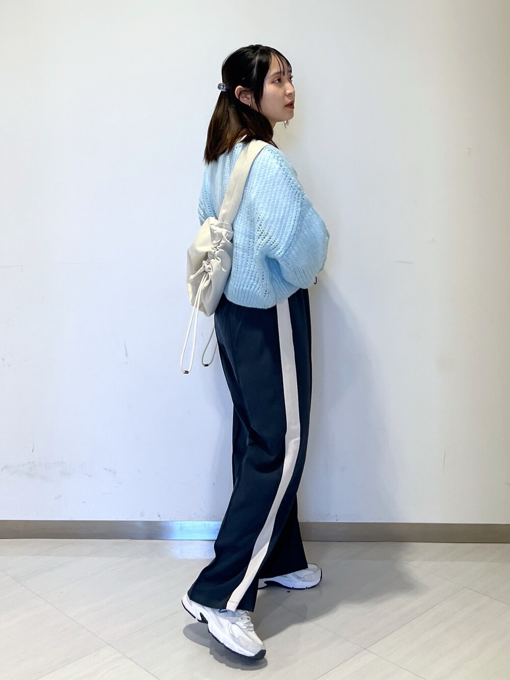 ホワイト系のショルダーバッグ、ブルー系のニット/セーター、ホワイト系のTシャツ/カットソーを着用したレディースの冬コーディネートの4枚目の写真