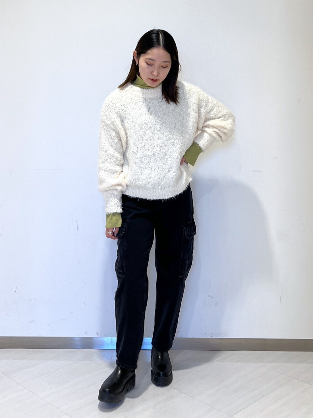 グリーン系のニット/セーター、ホワイト系のニット/セーター、ブラック系のデニムパンツを着用したレディースの冬コーディネートの2枚目の写真