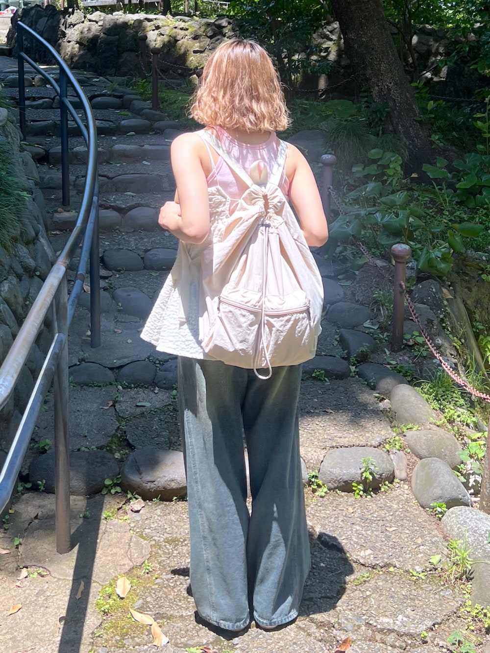 ピンク系のタンクトップ、ホワイト系のキャミソール、ブルー系のデニムパンツを着用したレディースの夏コーディネートの5枚目の写真