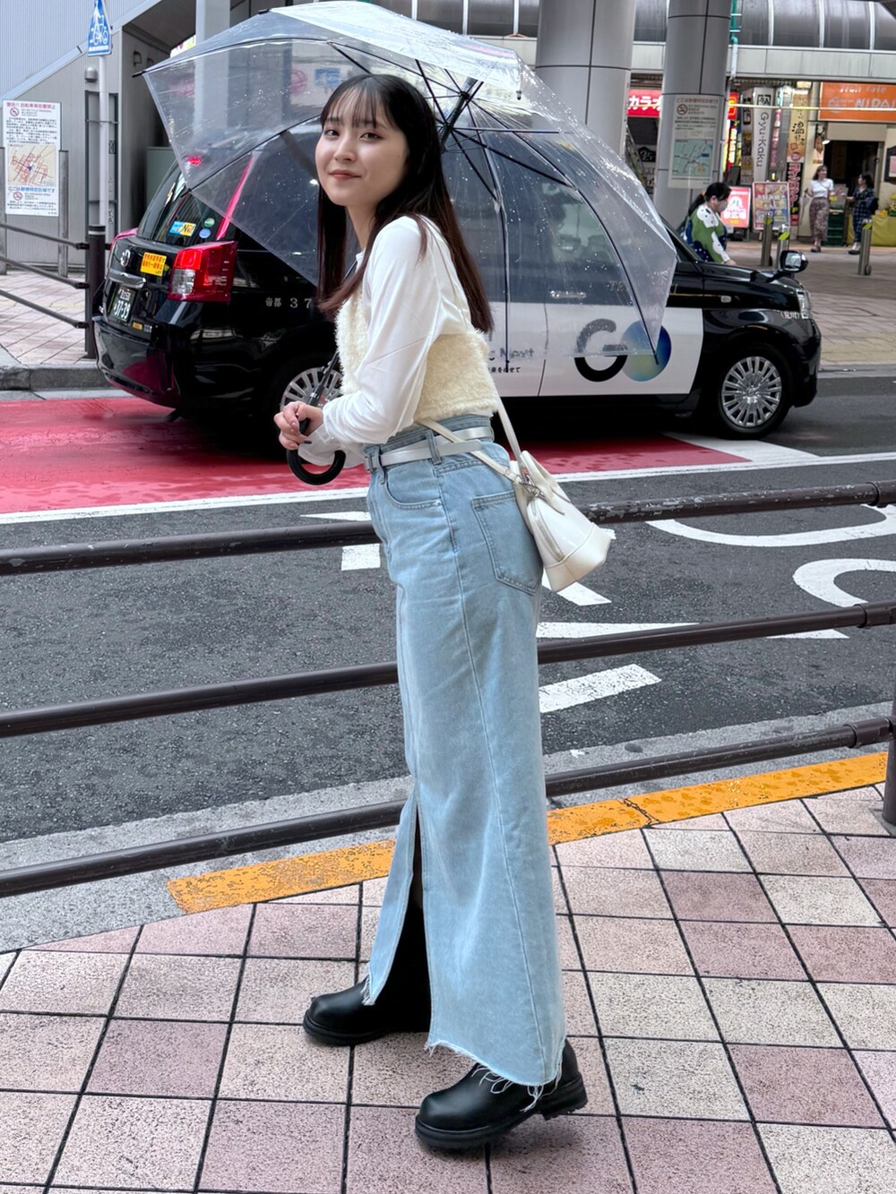 ブルー系のデニムスカート、ブラック系のブーツ、ホワイト系のキャミソールを着用したレディースの夏コーディネートの2枚目の写真