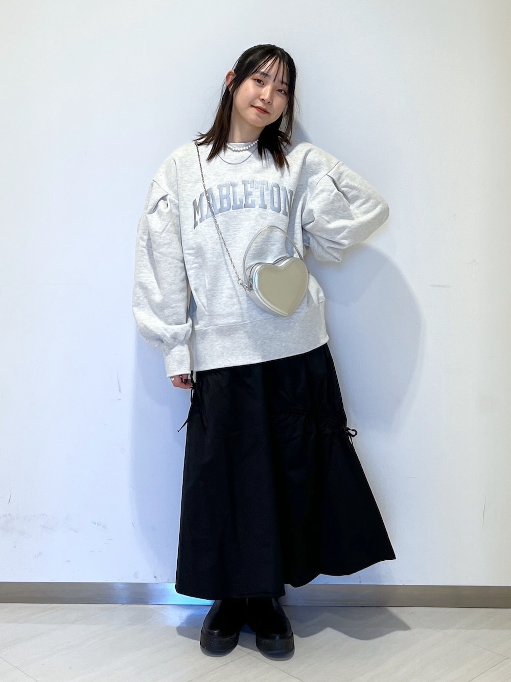 ホワイト系のスウェット、シルバー系のショルダーバッグ、ブラック系のスカートを着用したレディースの冬コーディネートの2枚目の写真