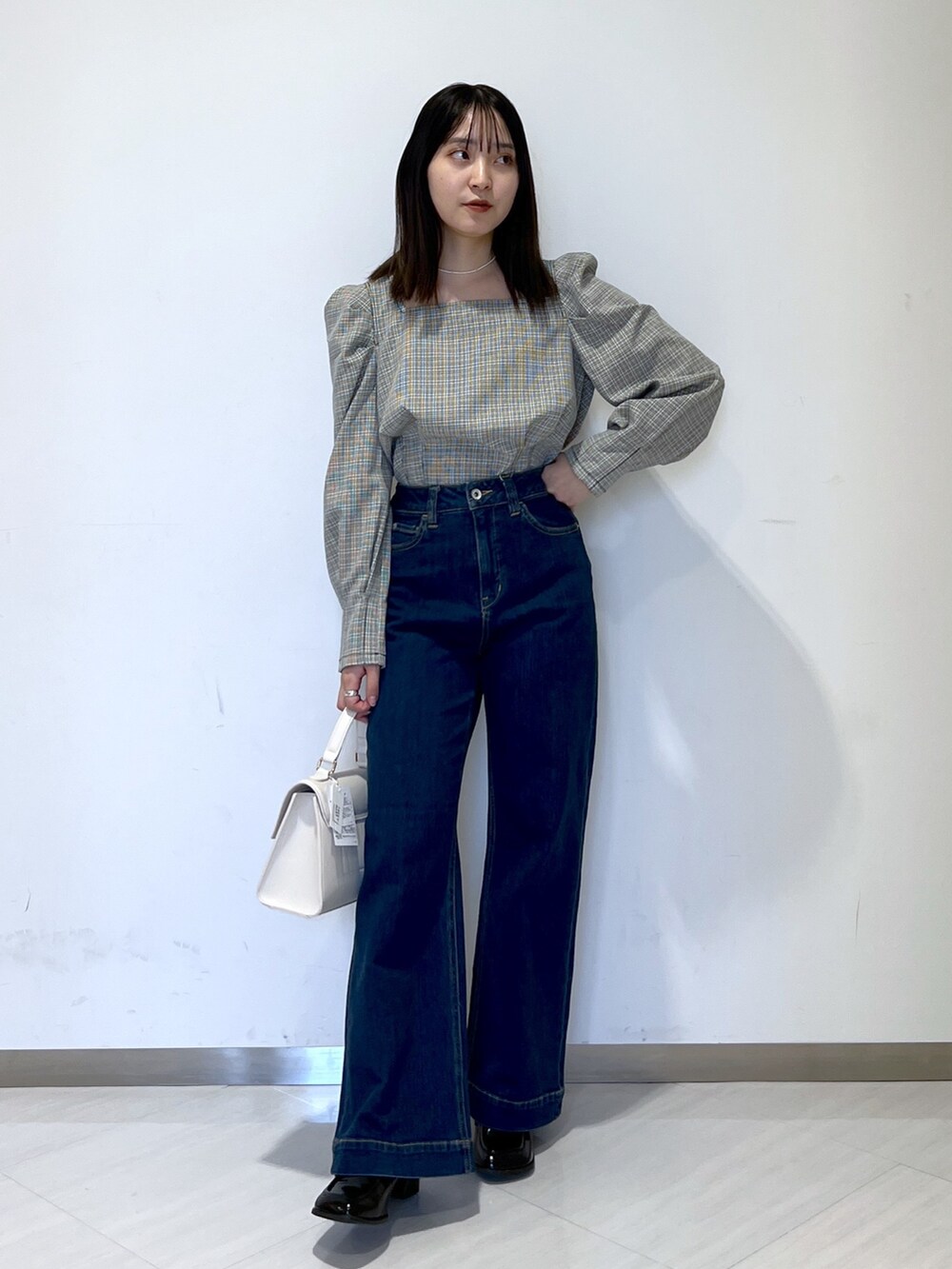 ベージュ系のノーカラーコート、ブラック系のシャツ/ブラウス、ブルー系のデニムパンツを着用したレディースの冬コーディネートの5枚目の写真