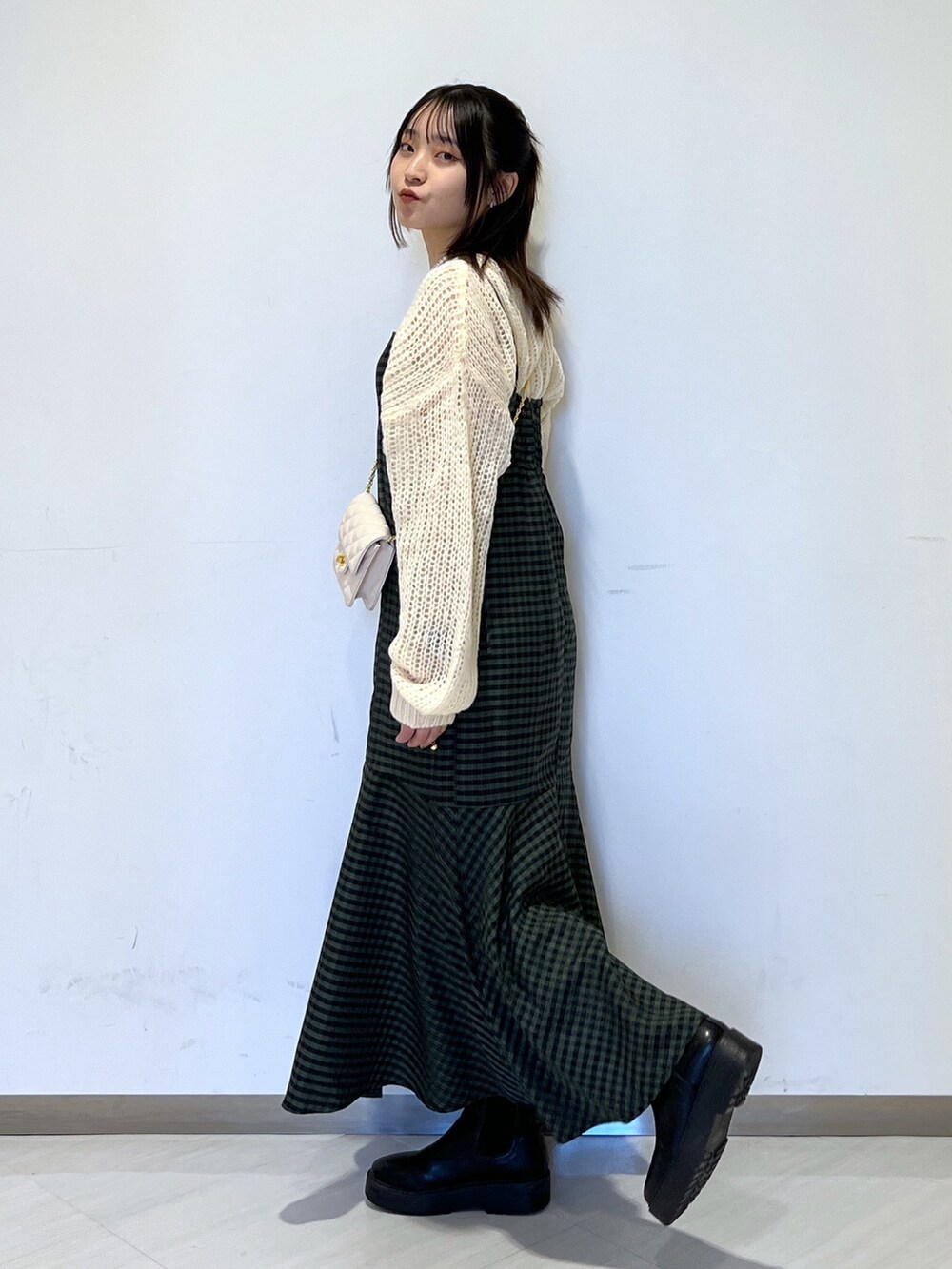 グリーン系のワンピース、ホワイト系のショルダーバッグ、ホワイト系のニット/セーターを着用したレディースの冬コーディネートの2枚目の写真