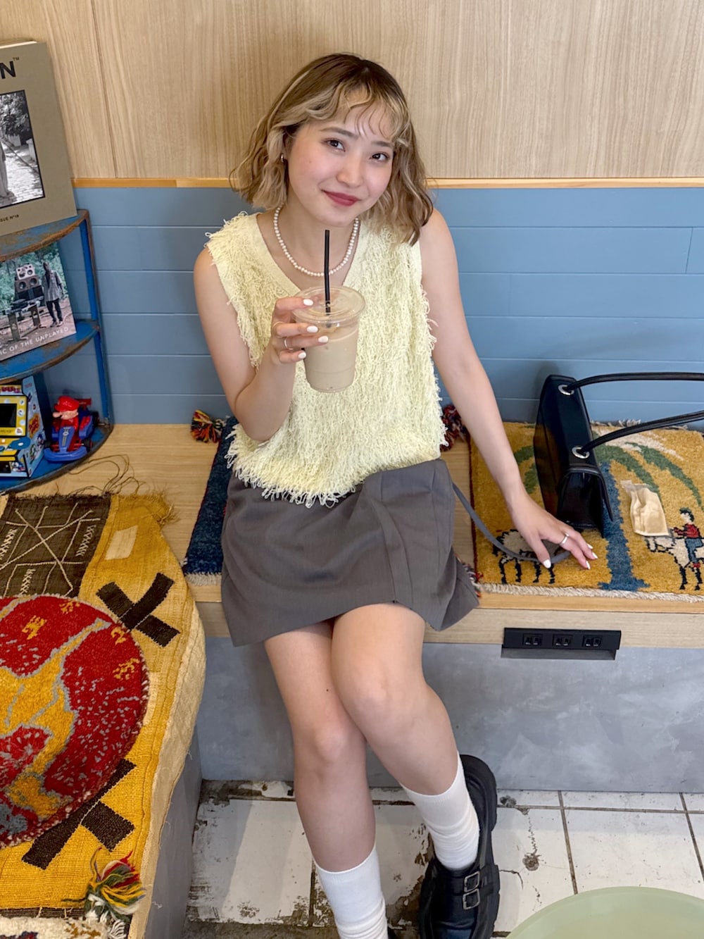 グレー系のスカート、イエロー系のニット/セーター、ホワイト系のキャミソールを着用したレディースの夏コーディネートの3枚目の写真