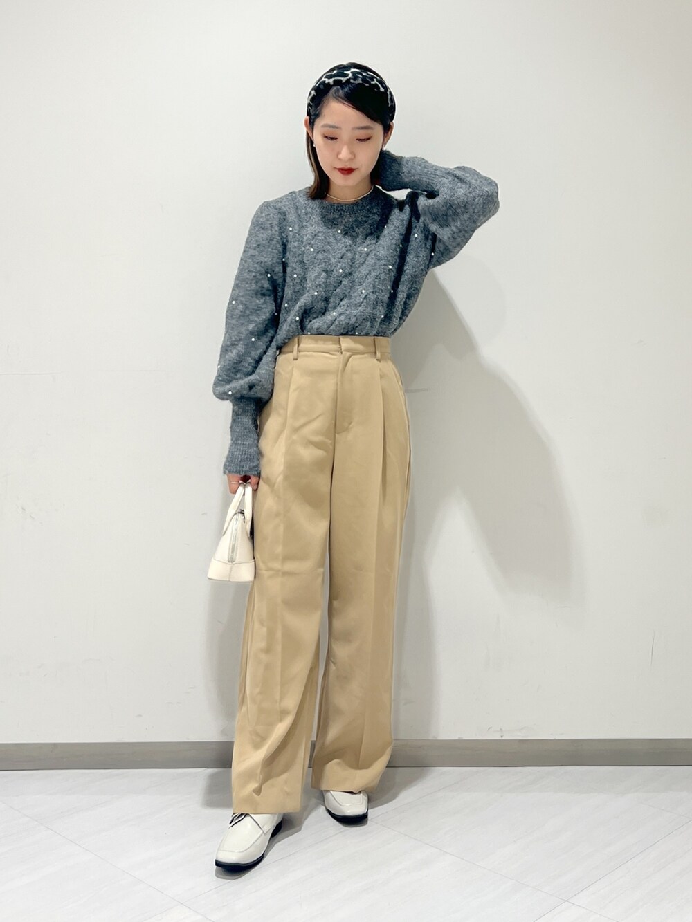 ベージュ系のスラックス、グレー系のニット/セーター、ホワイト系のショルダーバッグを着用したレディースの秋コーディネートの4枚目の写真