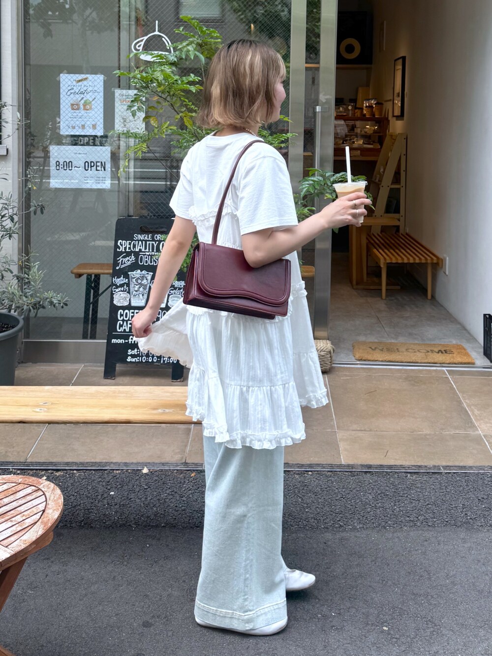 ホワイト系のワンピース、ホワイト系のTシャツ/カットソー、ブルー系のデニムパンツを着用したレディースの夏コーディネートの2枚目の写真