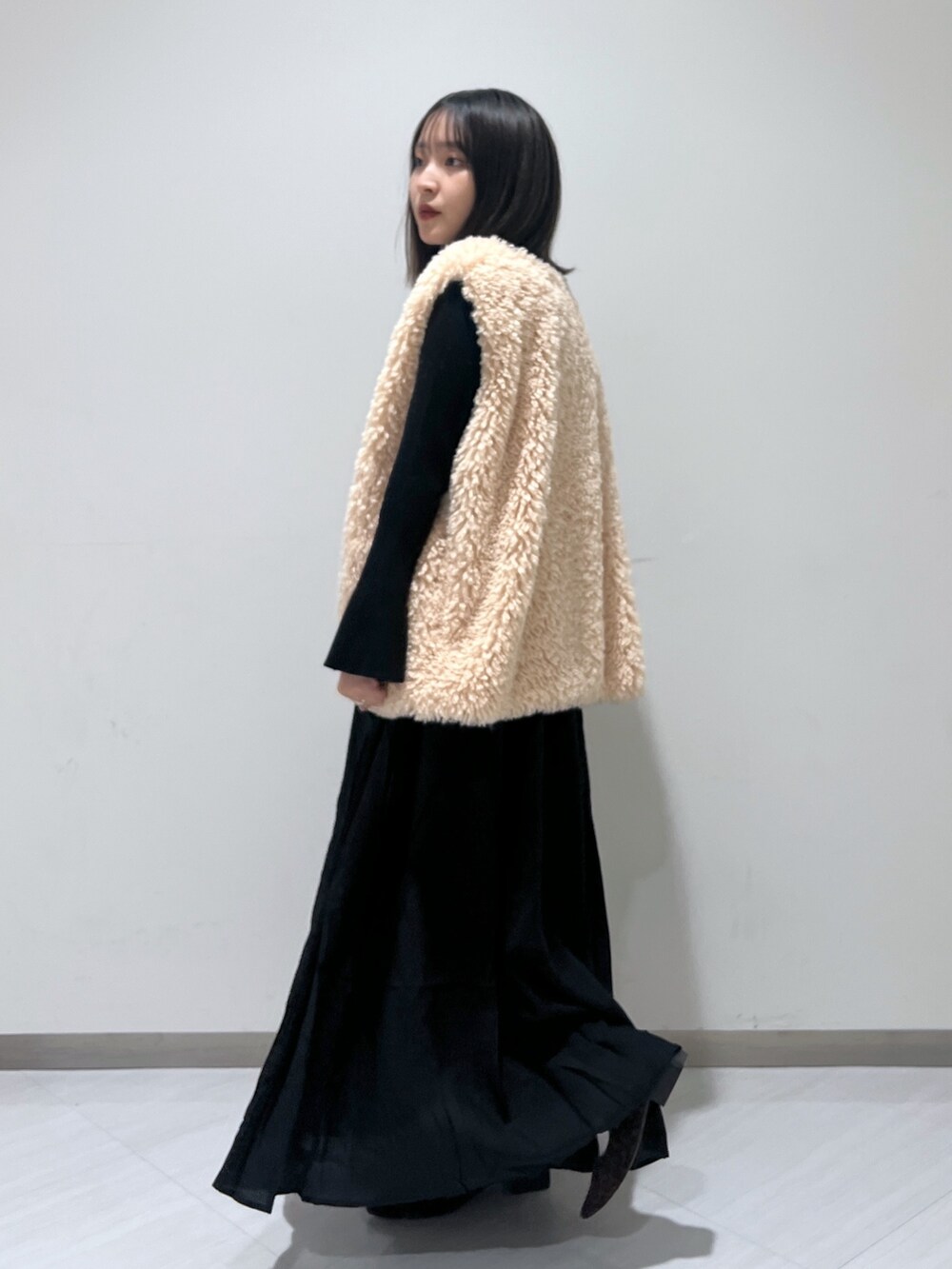 ブラック系のワンピース、ベージュ系のベスト、ブラウン系のバレエシューズを着用したレディースの秋コーディネートの4枚目の写真