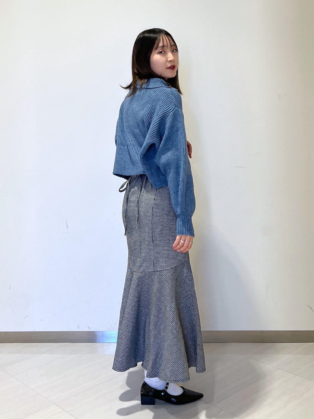 ブルー系のワンピース、ブラック系のスカート、ブラック系のバレエシューズを着用したレディースの冬コーディネートの4枚目の写真