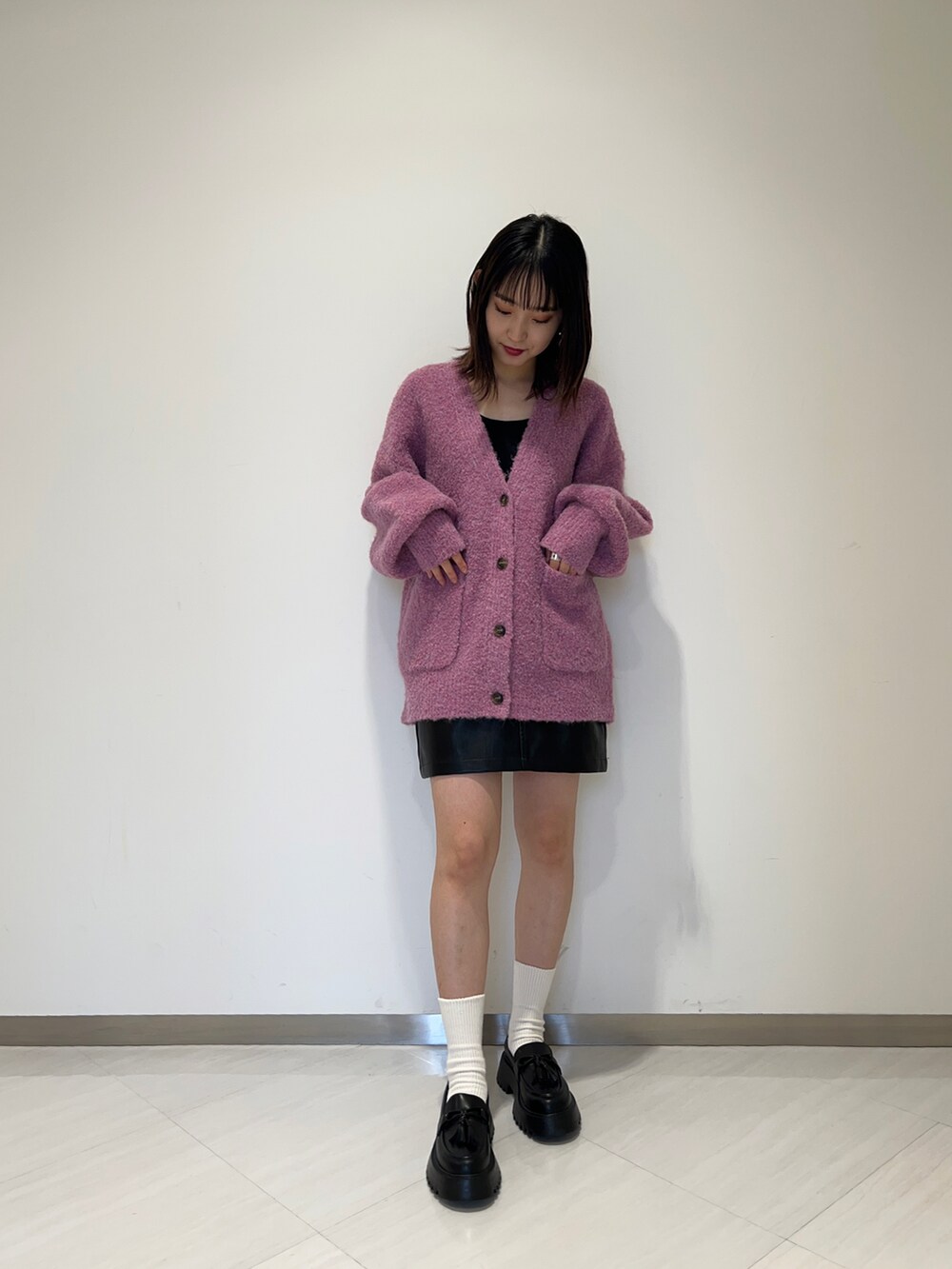 ブラック系のローファー、ピンク系のカーディガン/ボレロ、ブラック系のスカートを着用したレディースの秋コーディネートの2枚目の写真