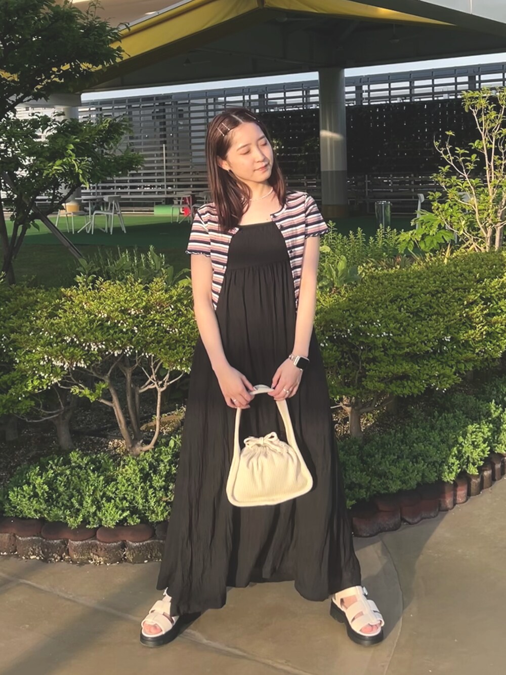 ホワイト系のトートバッグ、ブルー系のTシャツ/カットソー、ブラック系のワンピースを着用したレディースの春コーディネートの2枚目の写真