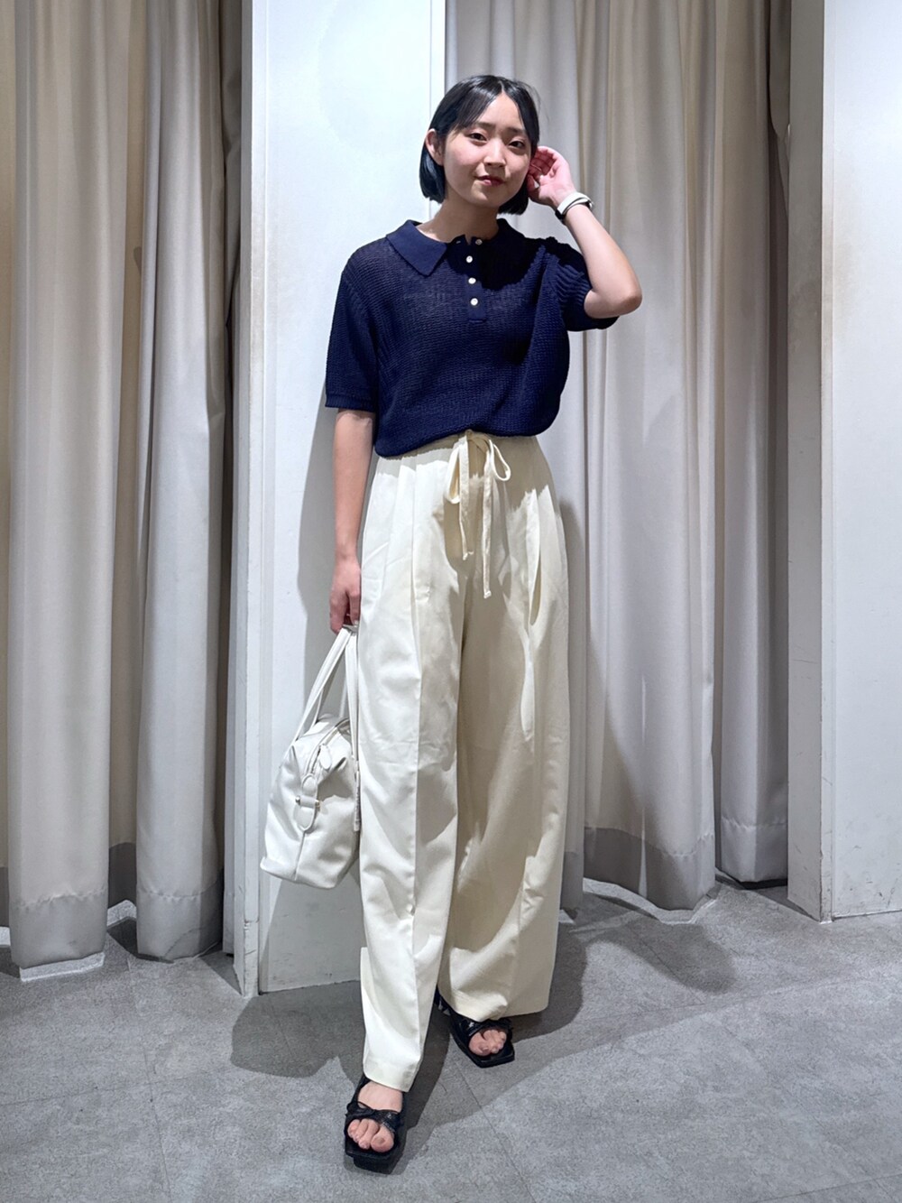 ブルー系のニット/セーター、ホワイト系のスラックス、ホワイト系のショルダーバッグを着用したレディースの夏コーディネートの2枚目の写真