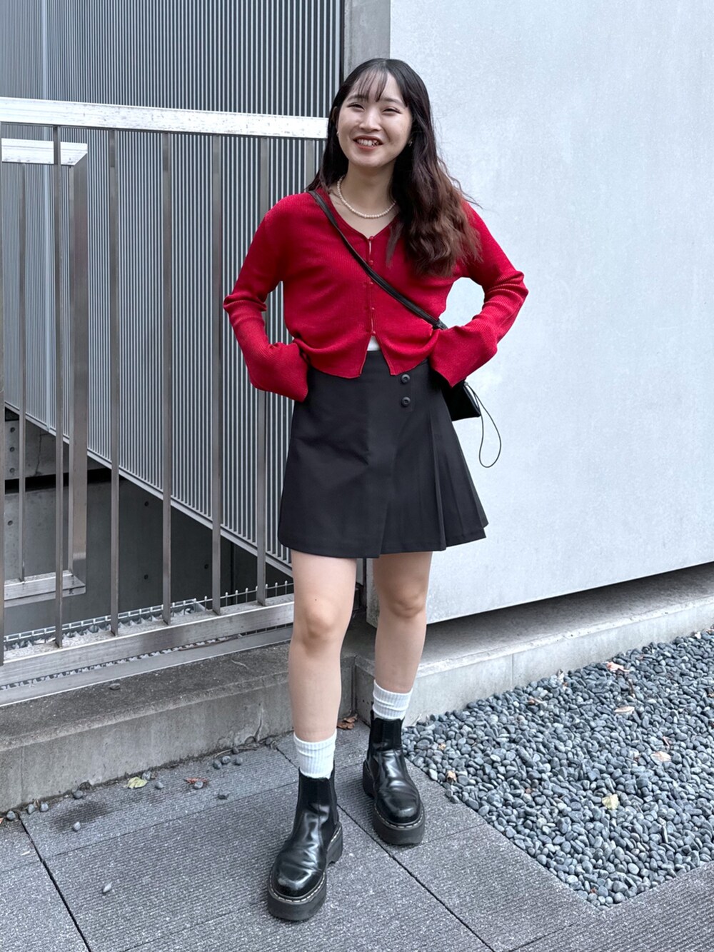ブラック系のスカート、レッド系のニット/セーター、ブラック系のトートバッグを着用したレディースの秋コーディネートの2枚目の写真