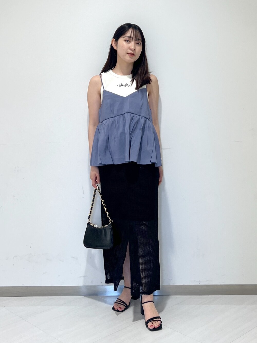 ホワイト系のタンクトップ、ブルー系のシャツ/ブラウス、ブラック系のトートバッグを着用したレディースの夏コーディネートの2枚目の写真