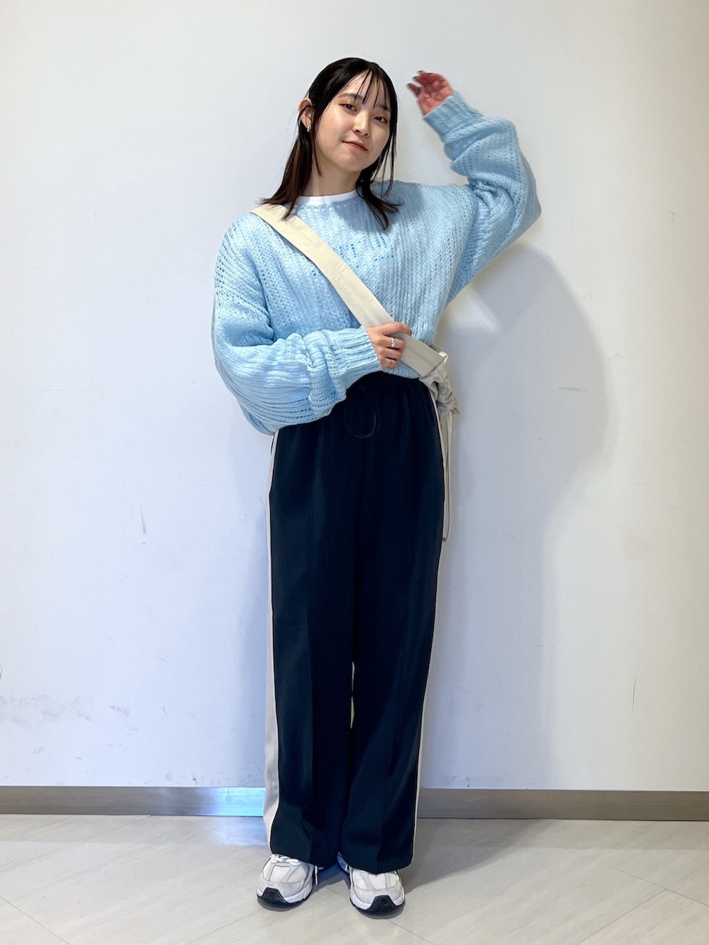 ホワイト系のショルダーバッグ、ブルー系のニット/セーター、ホワイト系のTシャツ/カットソーを着用したレディースの冬コーディネートの2枚目の写真