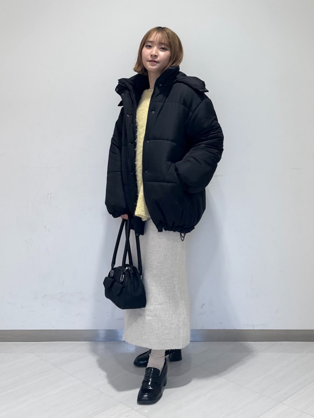 ブラック系のダウンジャケット/コート、イエロー系のニット/セーター、ブラック系のトートバッグを着用したレディースの冬コーディネートの3枚目の写真