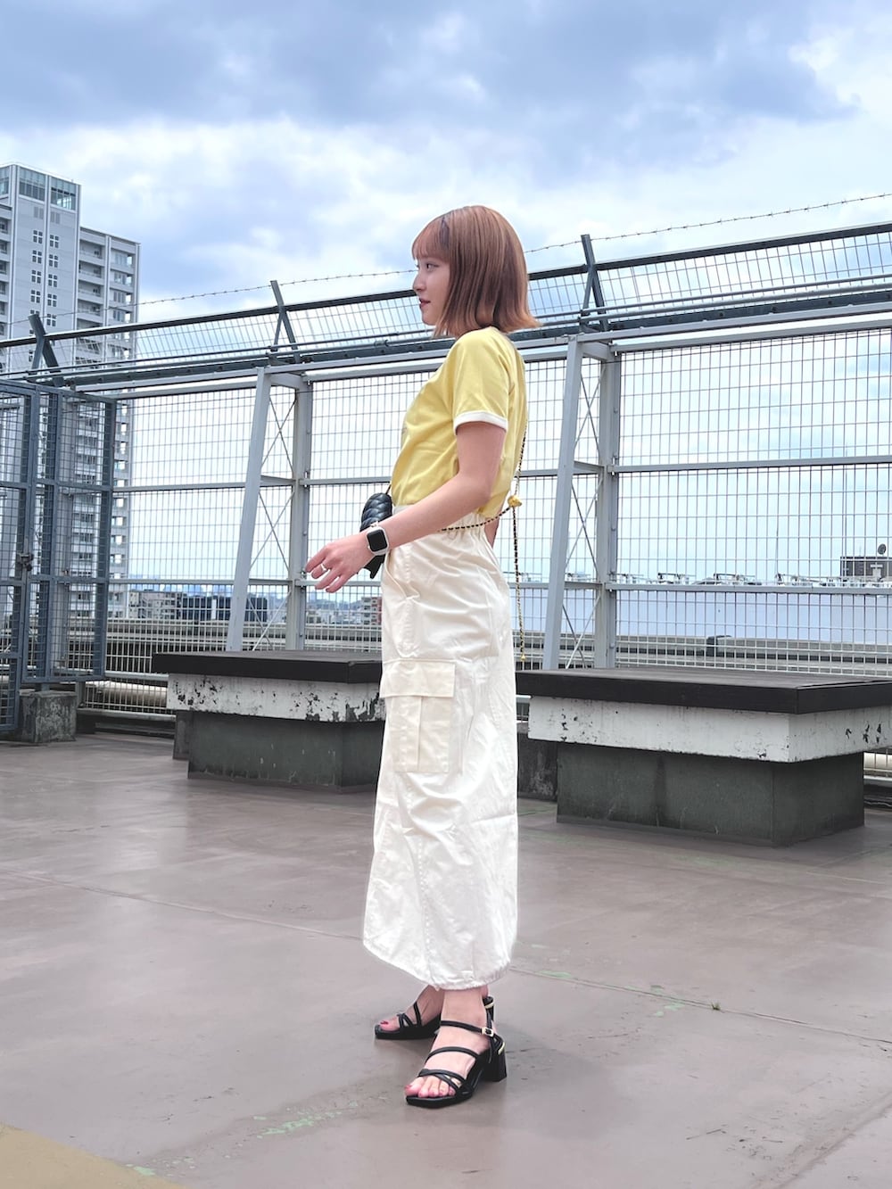 ホワイト系のスカート、イエロー系のTシャツ/カットソー、ブラック系のショルダーバッグを着用したレディースの夏コーディネートの3枚目の写真