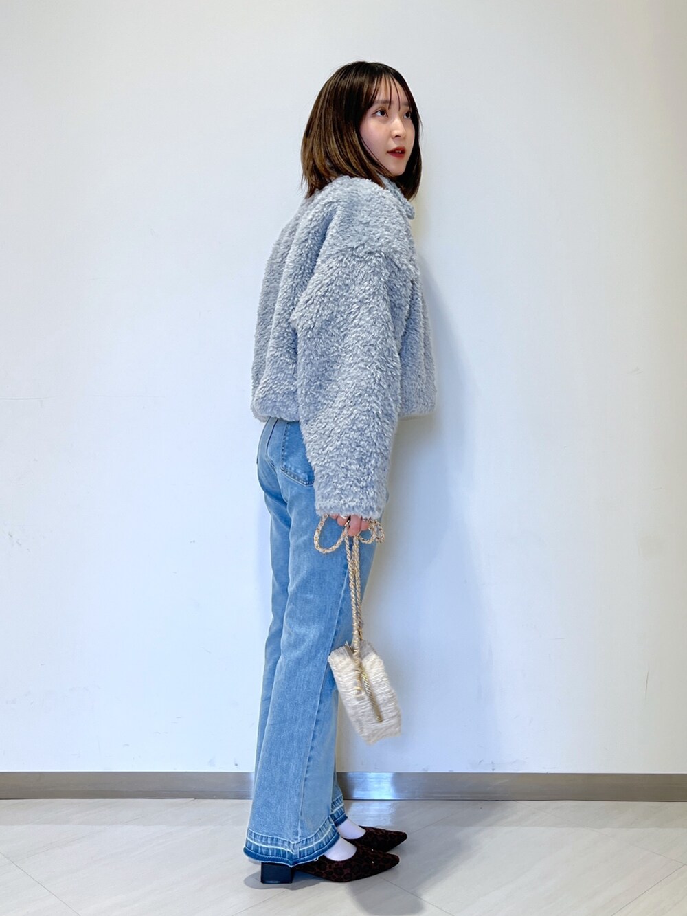 ブルー系のブルゾン、ブルー系のデニムパンツ、ベージュ系のショルダーバッグを着用したレディースの秋コーディネートの5枚目の写真
