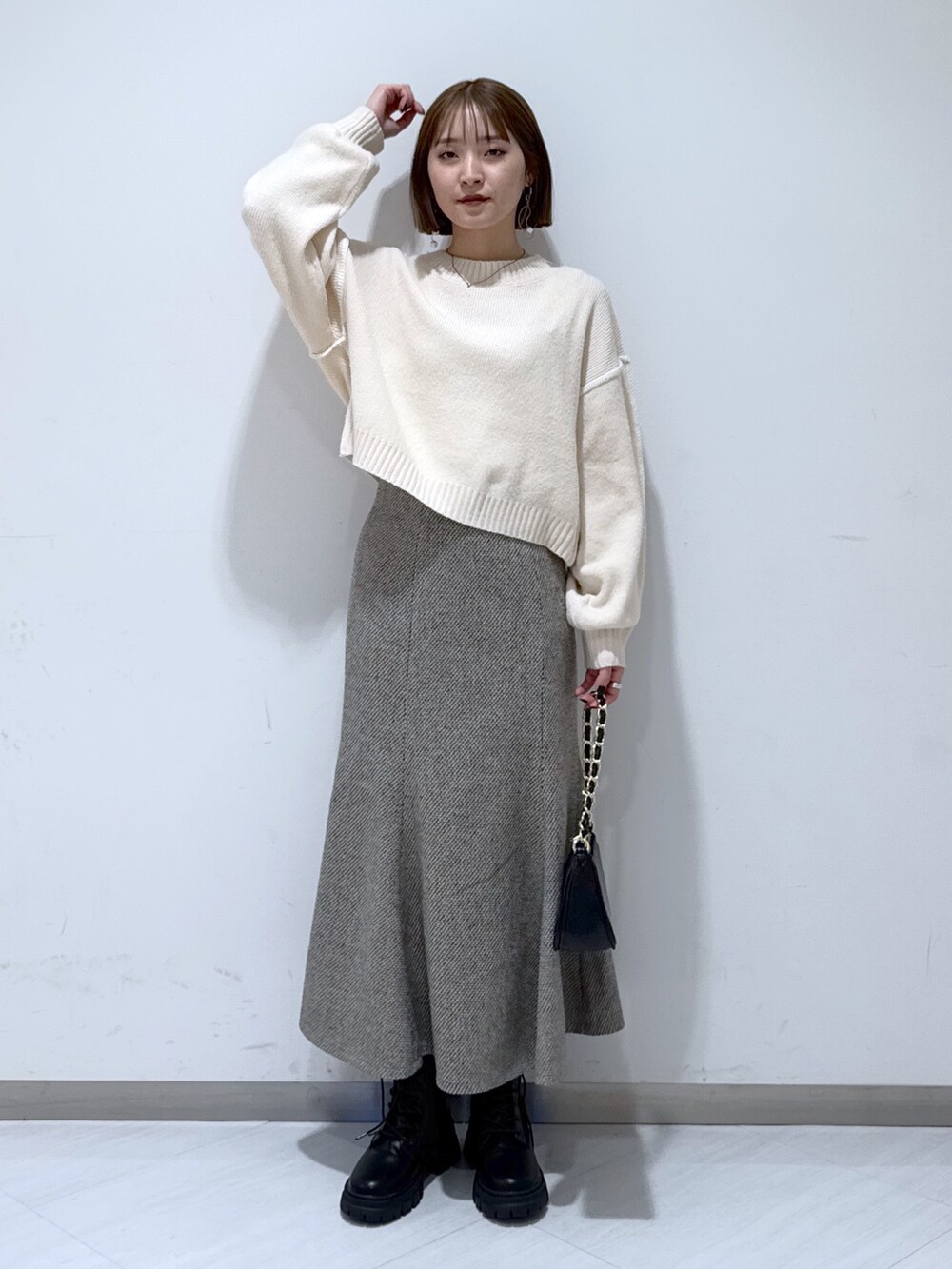ホワイト系のニット/セーター、ブラック系のトートバッグ、ベージュ系のスカートを着用したレディースの冬コーディネートの3枚目の写真