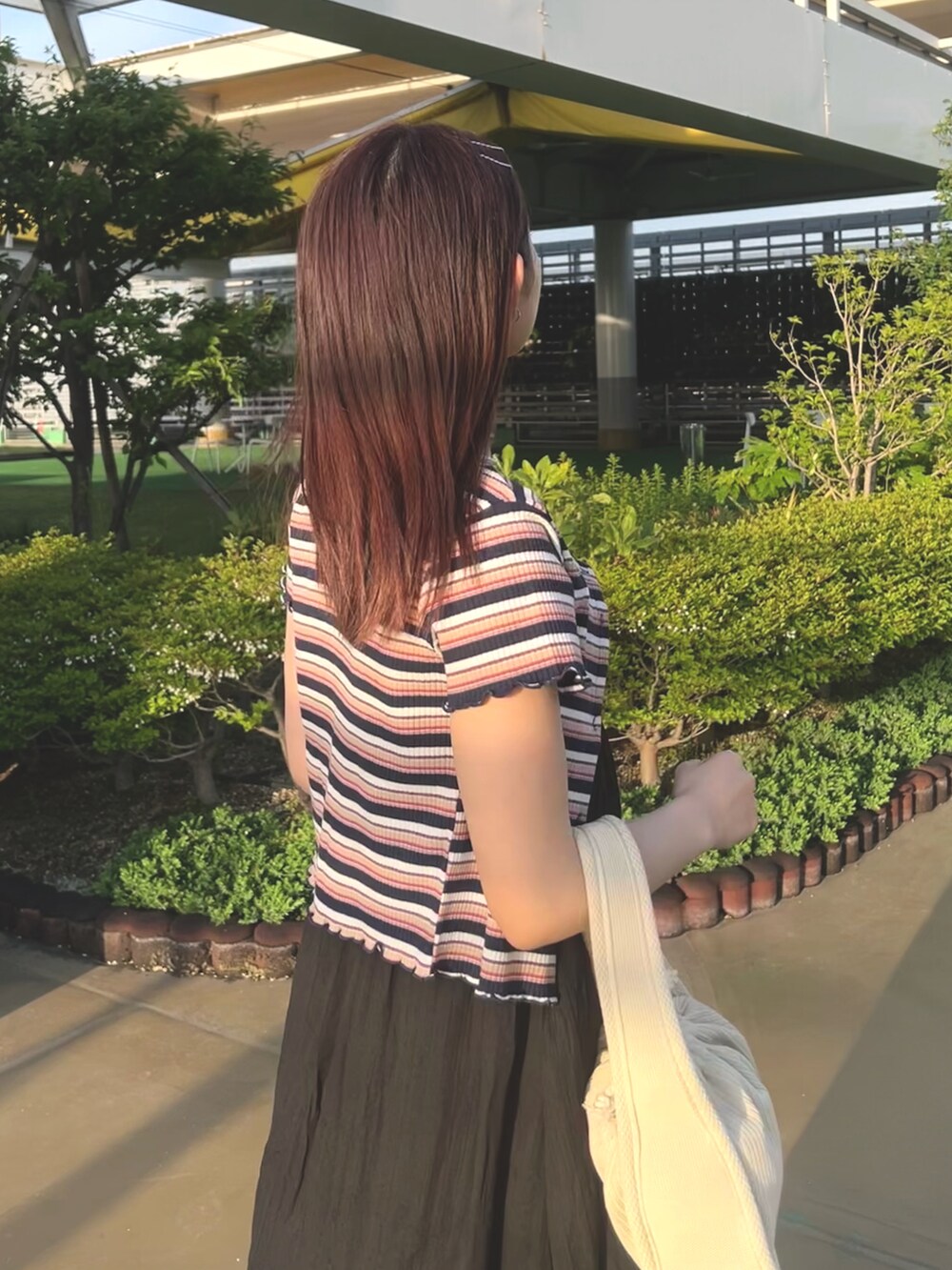 ホワイト系のトートバッグ、ブルー系のTシャツ/カットソー、ブラック系のワンピースを着用したレディースの春コーディネートの5枚目の写真