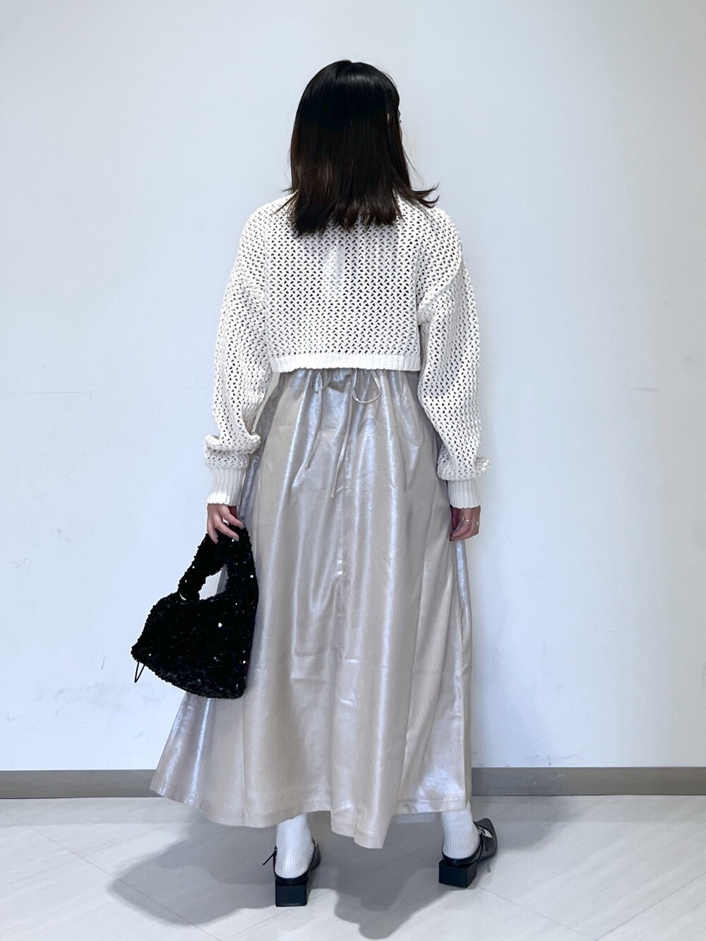 ベージュ系のニット/セーター、ブラック系のハンドバッグ、ベージュ系のワンピースを着用したレディースの春コーディネートの5枚目の写真