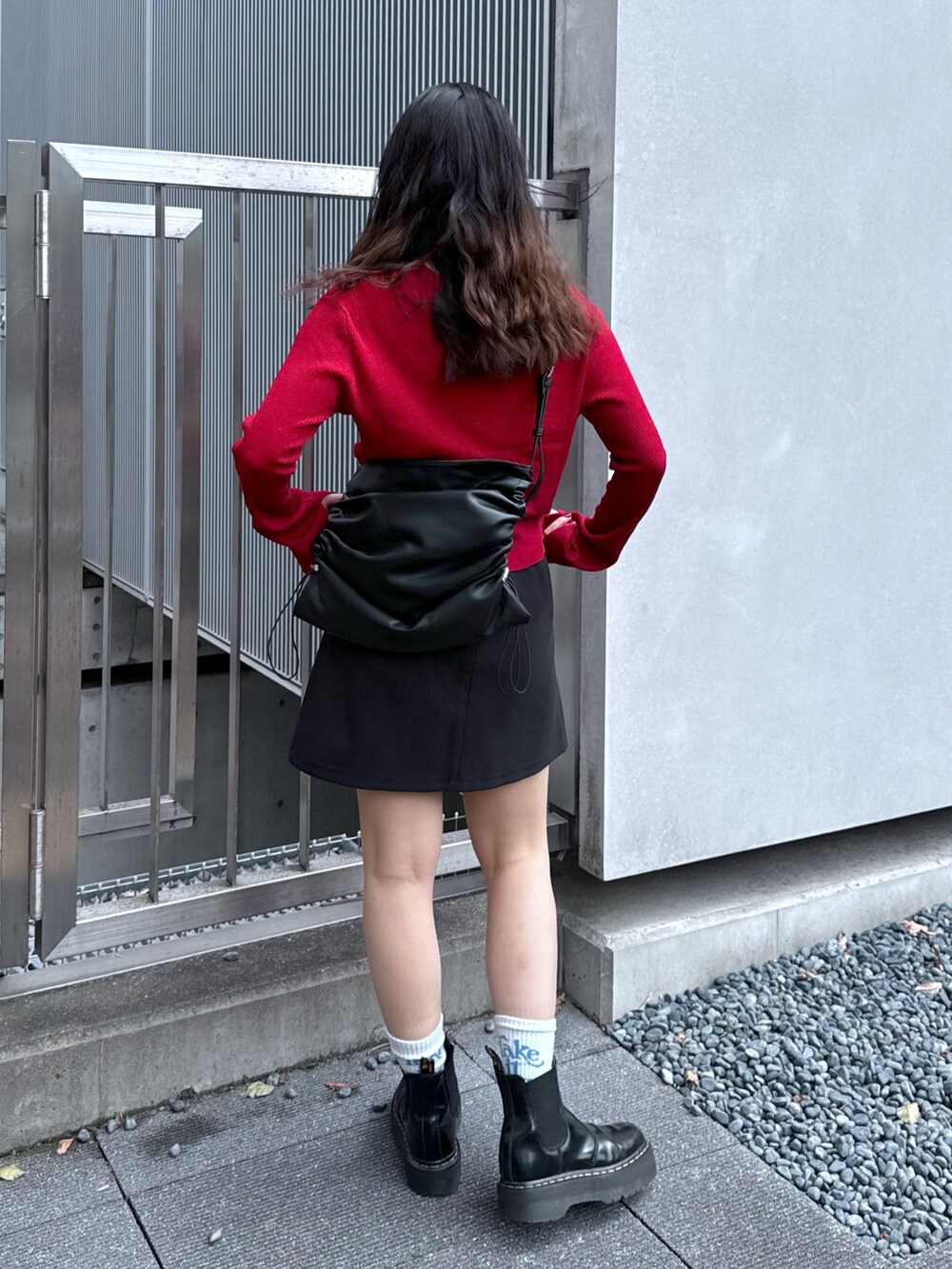 ブラック系のスカート、レッド系のニット/セーター、ブラック系のトートバッグを着用したレディースの秋コーディネートの3枚目の写真