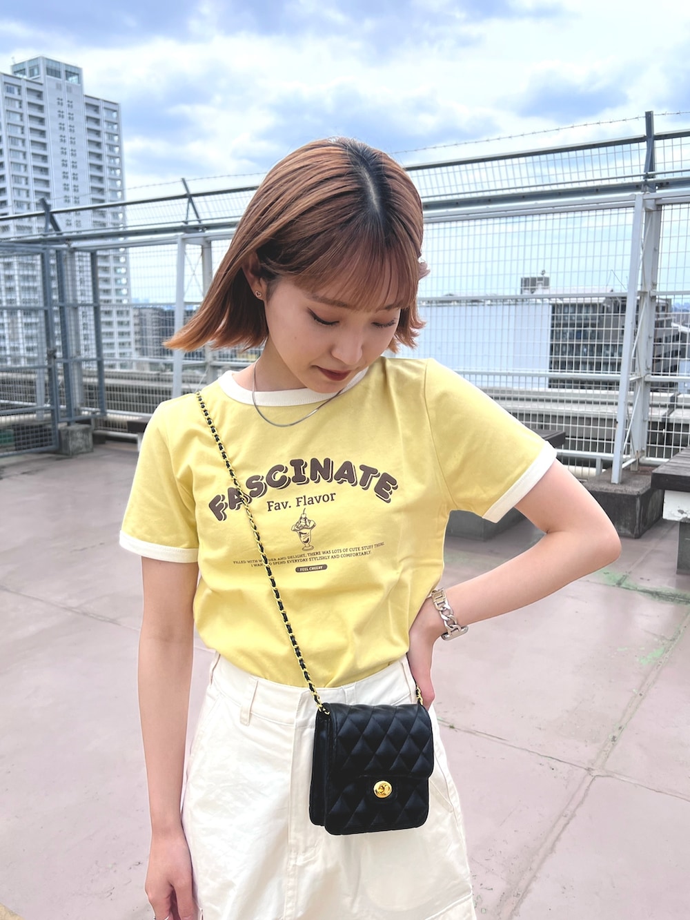 ホワイト系のスカート、イエロー系のTシャツ/カットソー、ブラック系のショルダーバッグを着用したレディースの夏コーディネートの6枚目の写真