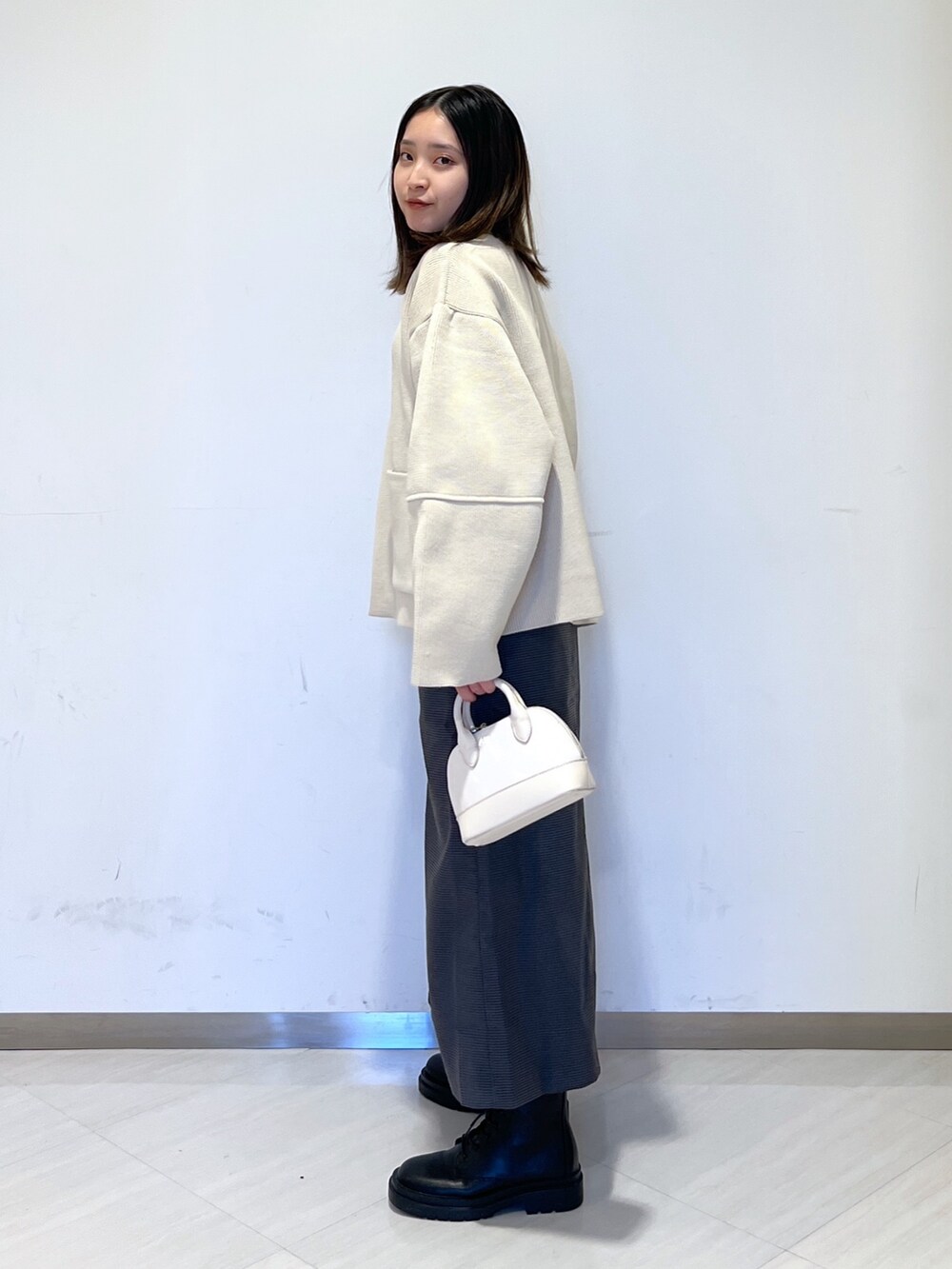 ホワイト系のカーディガン/ボレロ、ブラック系のニット/セーター、ホワイト系のショルダーバッグを着用したレディースの冬コーディネートの4枚目の写真