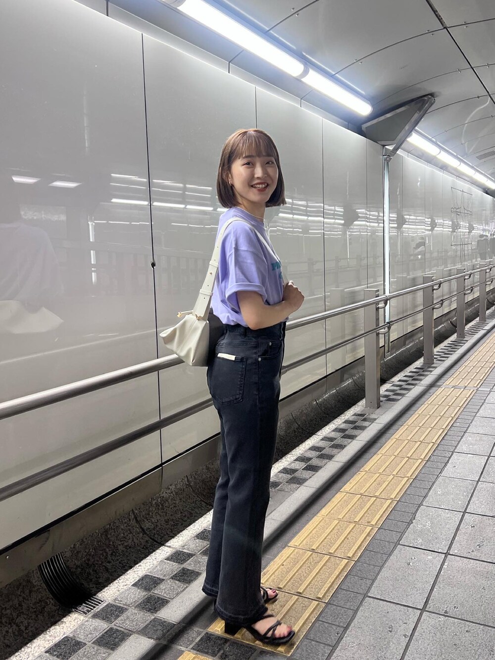 ブラック系のデニムパンツ、パープル系のTシャツ/カットソー、ホワイト系のボディバッグ/ウエストポーチを着用したレディースの春コーディネートの3枚目の写真