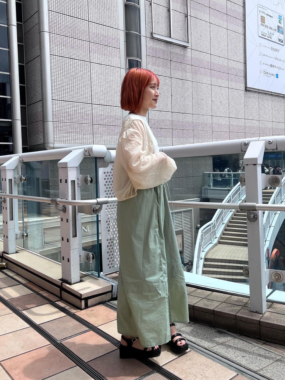 グリーン系のワンピース、ホワイト系のシャツ/ブラウス、ブラック系のサンダルを着用したレディースの春コーディネートの3枚目の写真