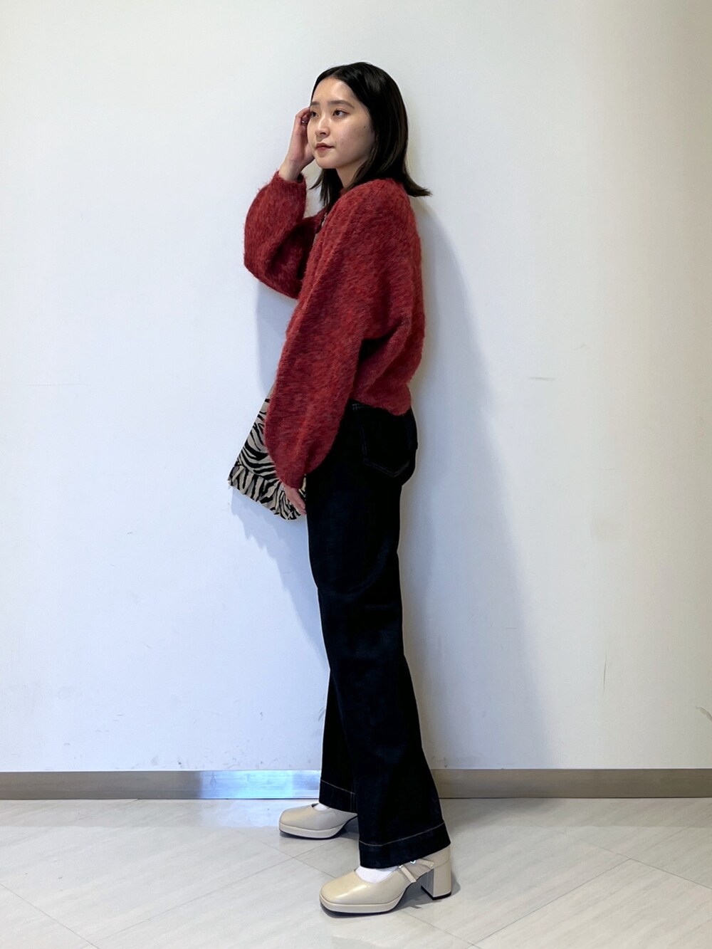 ブルー系のデニムパンツ、レッド系のニット/セーター、ベージュ系のトートバッグを着用したレディースの秋コーディネートの3枚目の写真