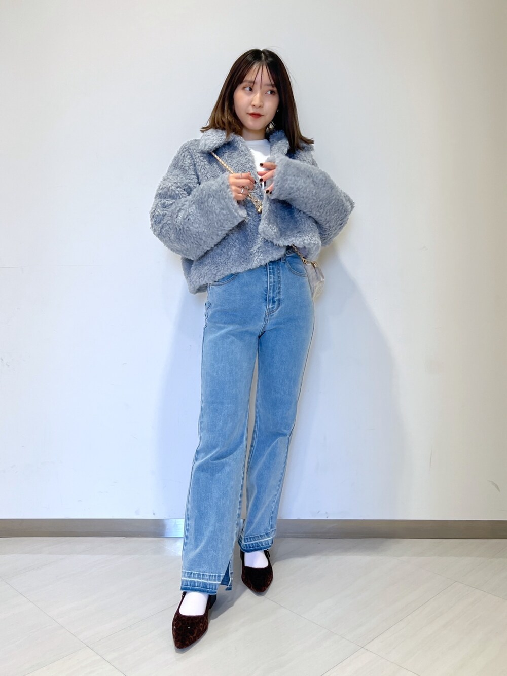 ブルー系のブルゾン、ブルー系のデニムパンツ、ベージュ系のショルダーバッグを着用したレディースの秋コーディネートの2枚目の写真