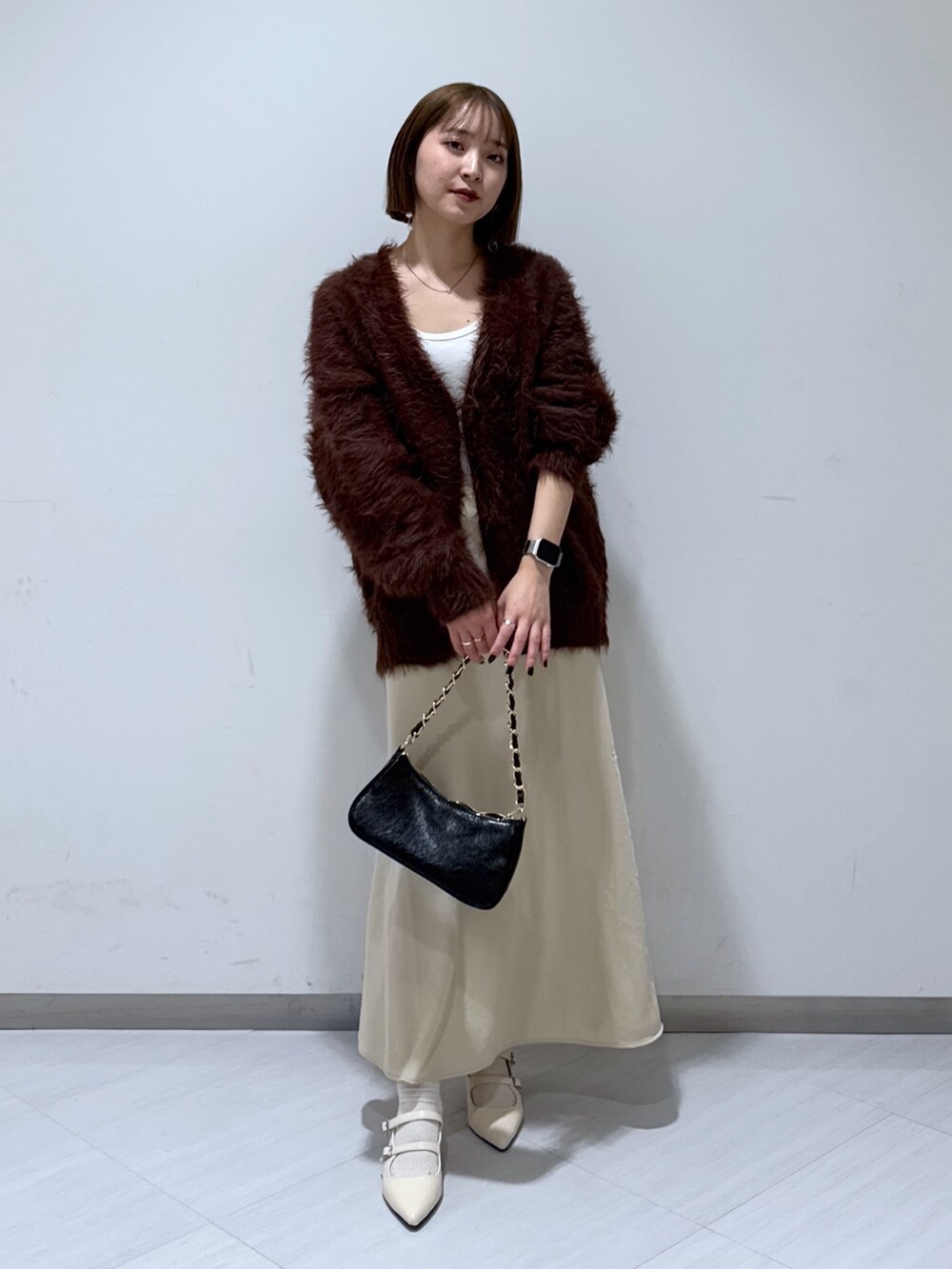 ブラウン系のカーディガン/ボレロ、ホワイト系のタンクトップ、ベージュ系のスカートを着用したレディースの冬コーディネートの3枚目の写真