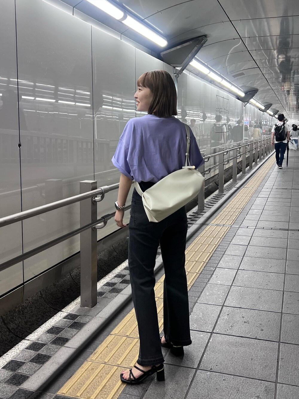 ブラック系のデニムパンツ、パープル系のTシャツ/カットソー、ホワイト系のボディバッグ/ウエストポーチを着用したレディースの春コーディネートの2枚目の写真