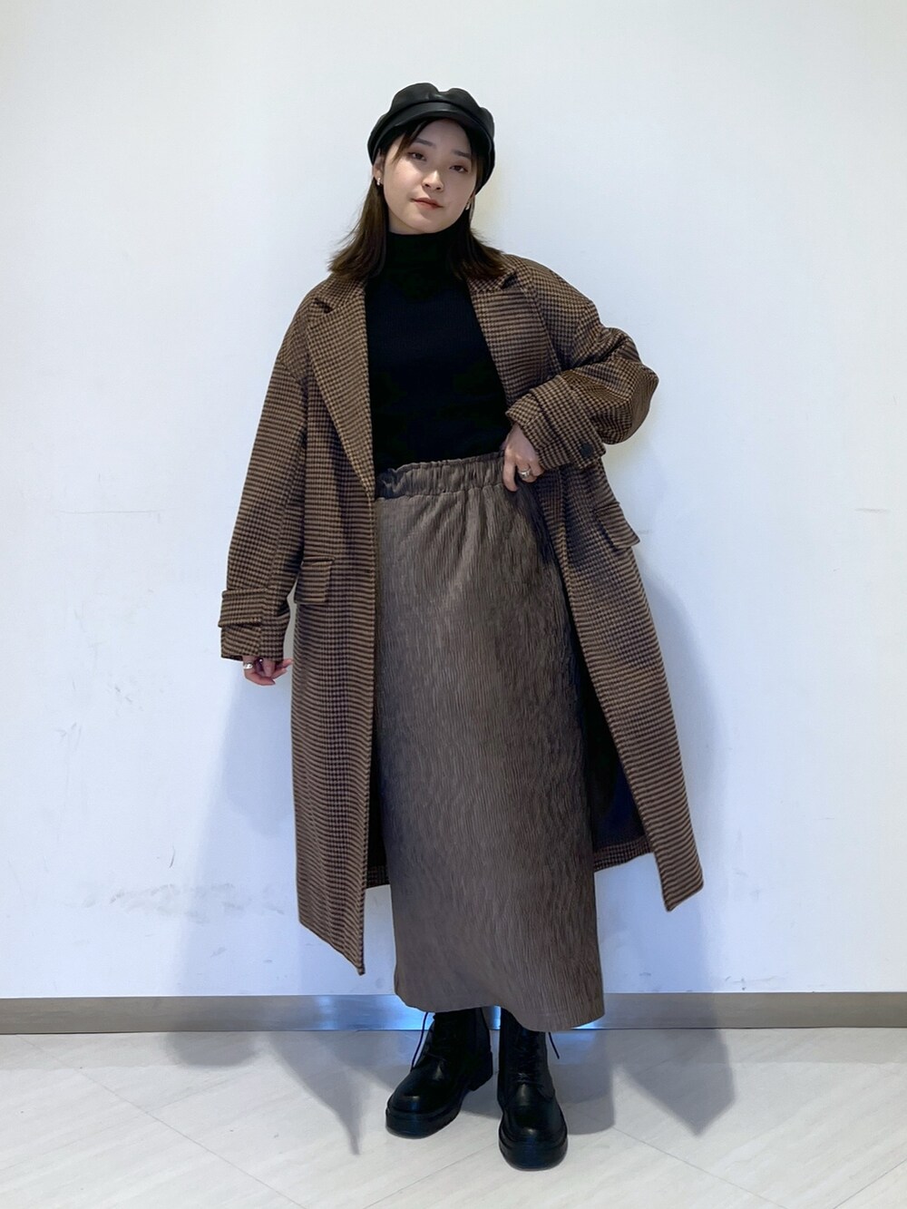 ブラウン系のチェスターコート、ブラック系のニット/セーター、ブラウン系のスカートを着用したレディースの冬コーディネートの4枚目の写真