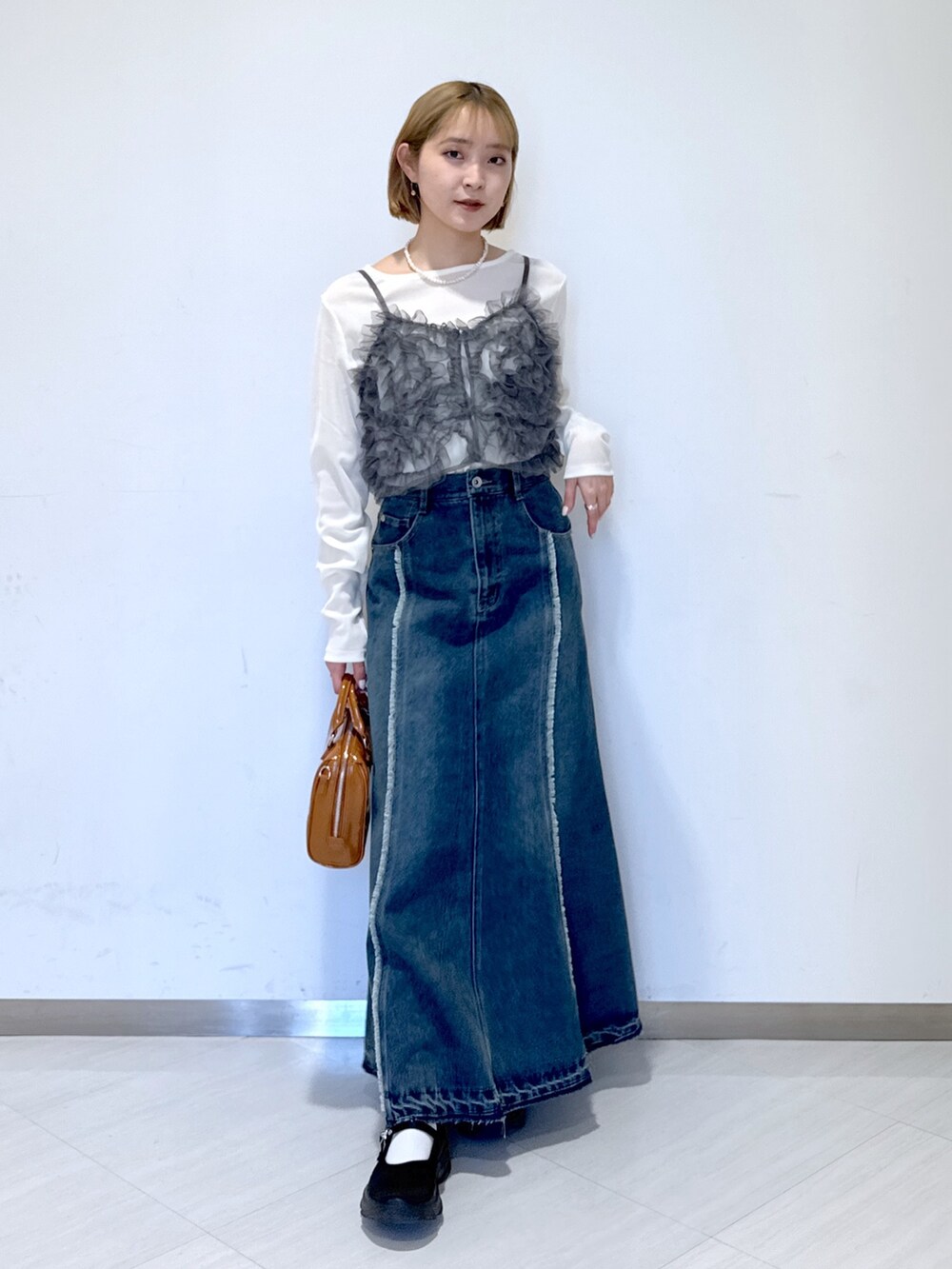 ブラック系のスニーカー、ブルー系のスカート、ベージュ系のショルダーバッグを着用したレディースの冬コーディネートの4枚目の写真