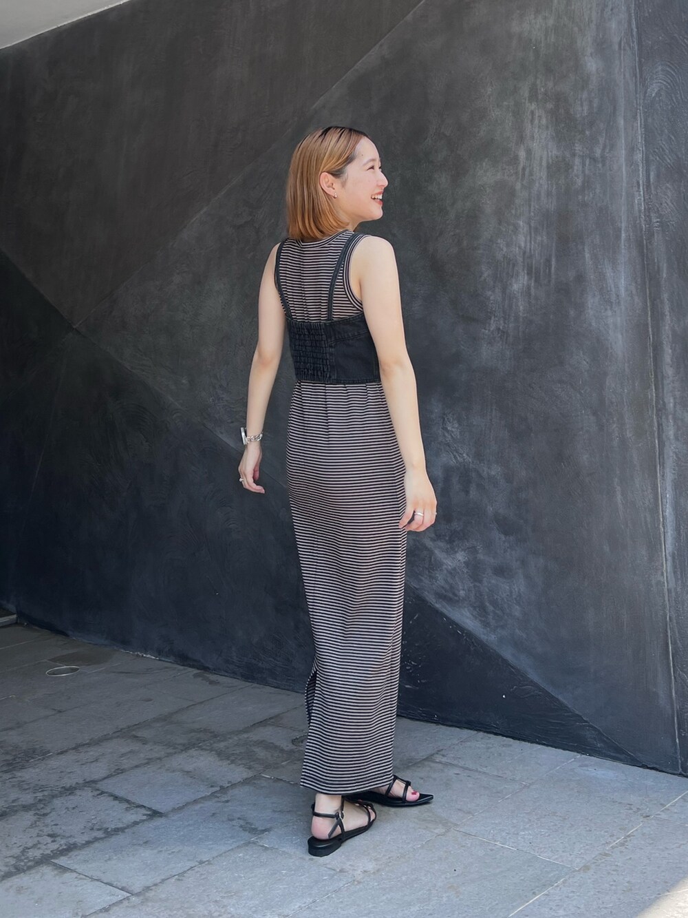 ブラウン系のワンピース、ブラック系のベスト、ブラック系のサンダルを着用したレディースの夏コーディネートの3枚目の写真