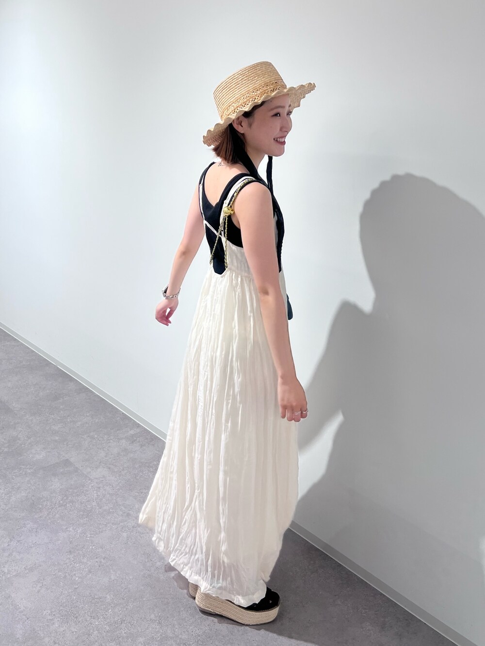 ブラック系のニット/セーター、ホワイト系のワンピース、ブルー系のショルダーバッグを着用したレディースの夏コーディネートの4枚目の写真