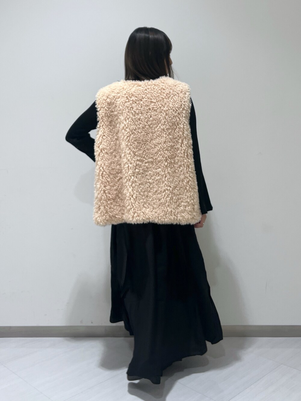 ブラック系のワンピース、ベージュ系のベスト、ブラウン系のバレエシューズを着用したレディースの秋コーディネートの6枚目の写真