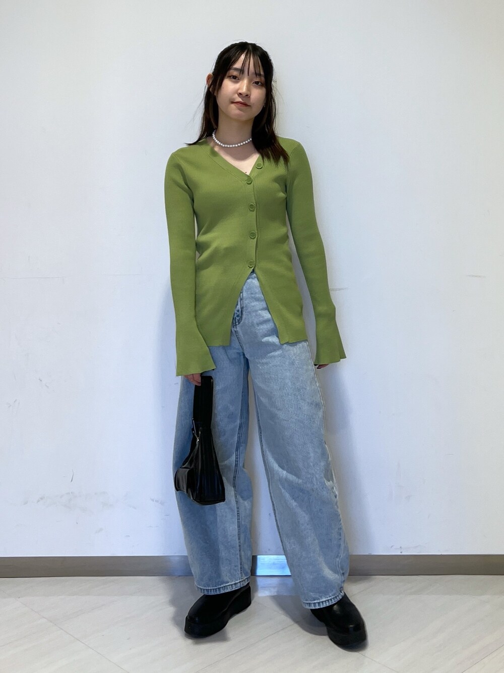 グリーン系のカーディガン/ボレロ、ブラック系のショルダーバッグ、ブルー系のデニムパンツを着用したレディースの冬コーディネートの2枚目の写真