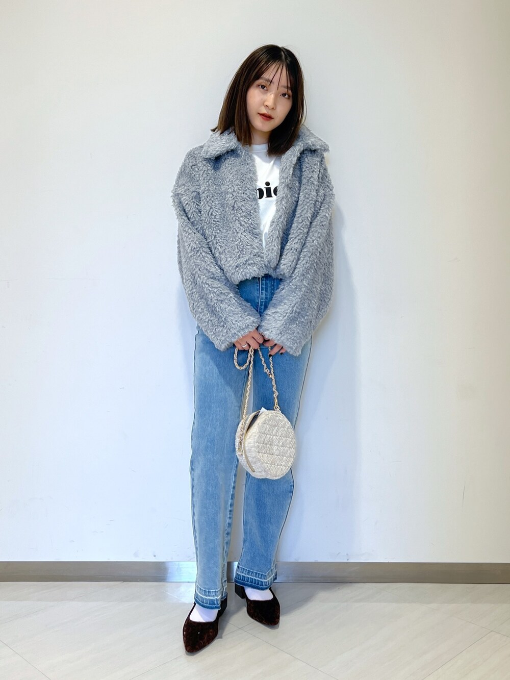 ブルー系のブルゾン、ブルー系のデニムパンツ、ベージュ系のショルダーバッグを着用したレディースの秋コーディネートの3枚目の写真